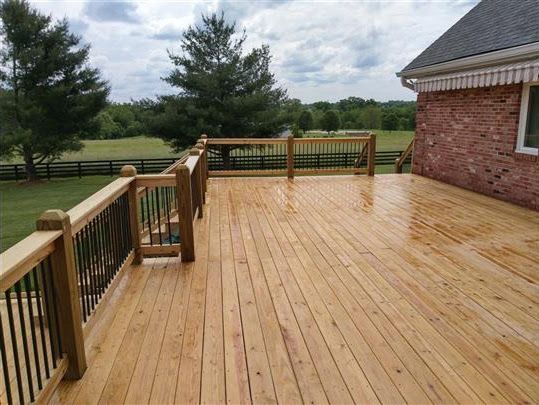 A large wooden deck with a brick house in the background.