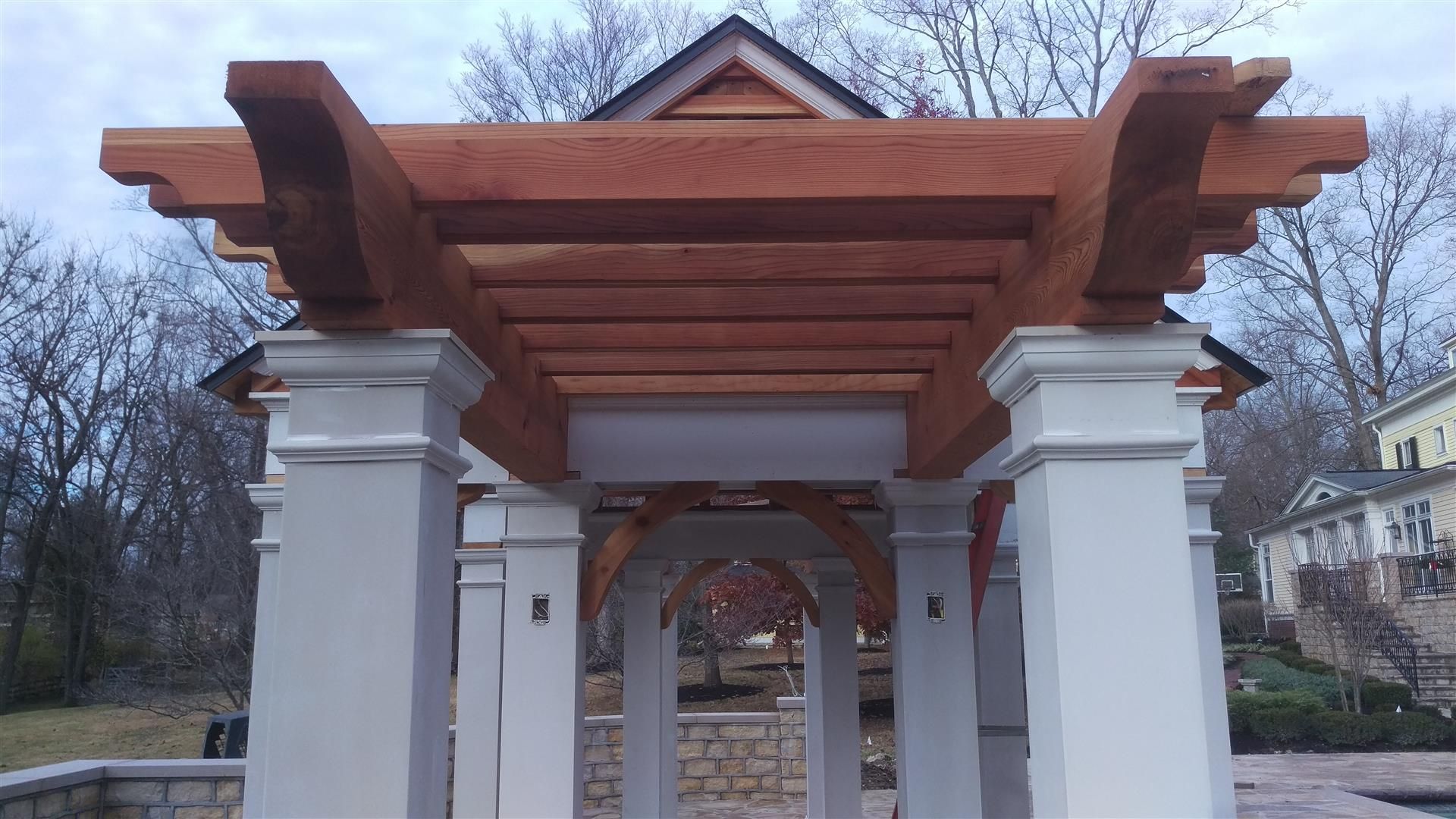 A wooden pergola is sitting on top of a white building.