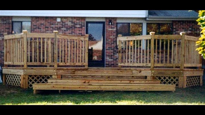 A wooden deck is sitting in front of a brick house.