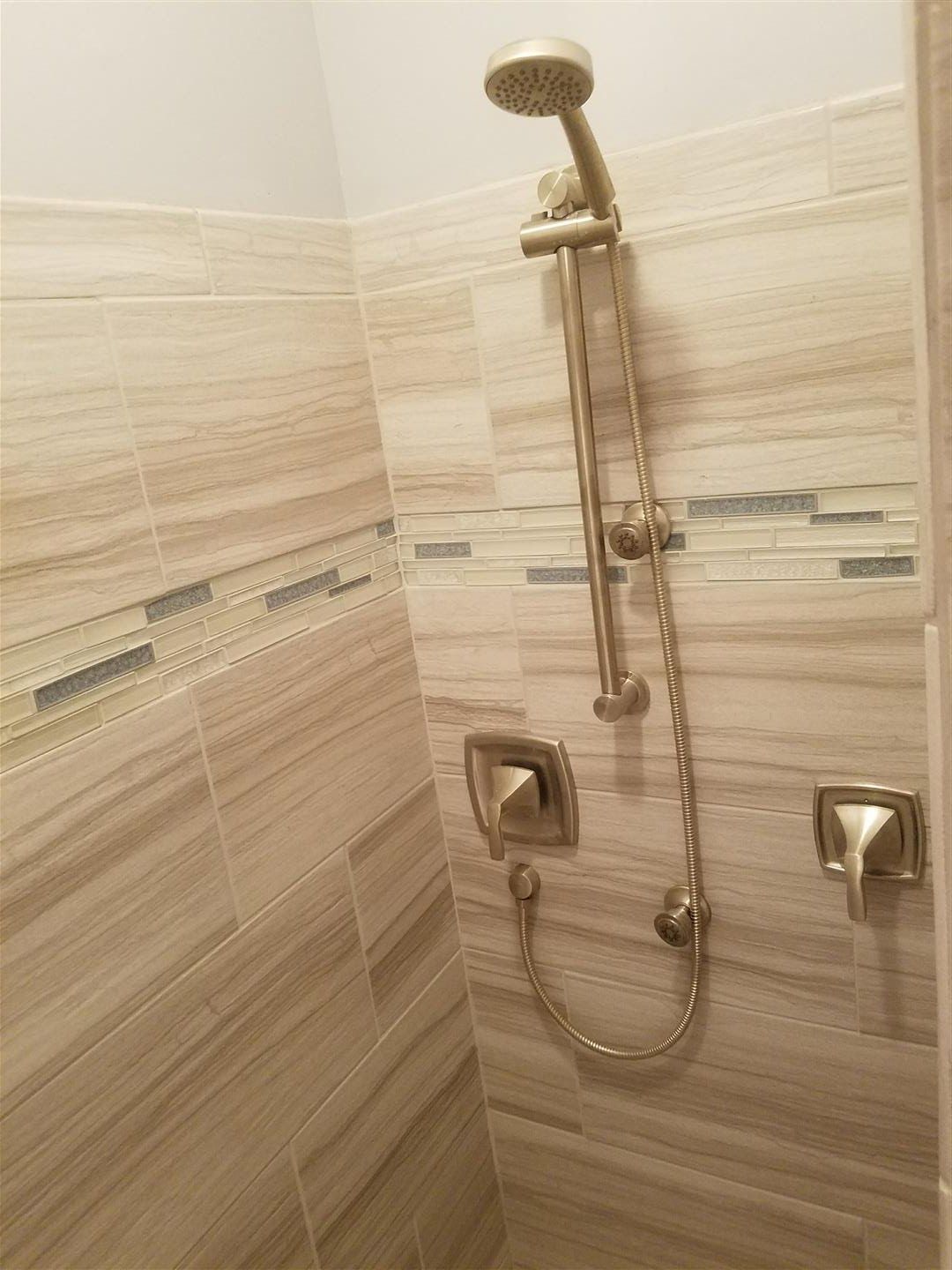A shower with a shower head and a hose in a bathroom.