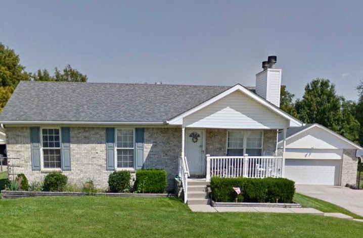 A brick house with a gray roof and blue shutters
