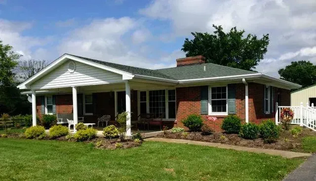 A brick house with a porch and a green roof
