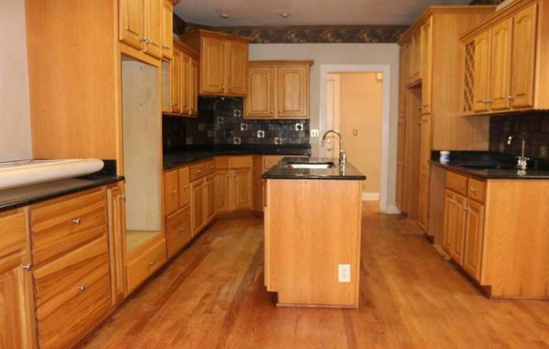 An empty kitchen with wooden cabinets and black counter tops