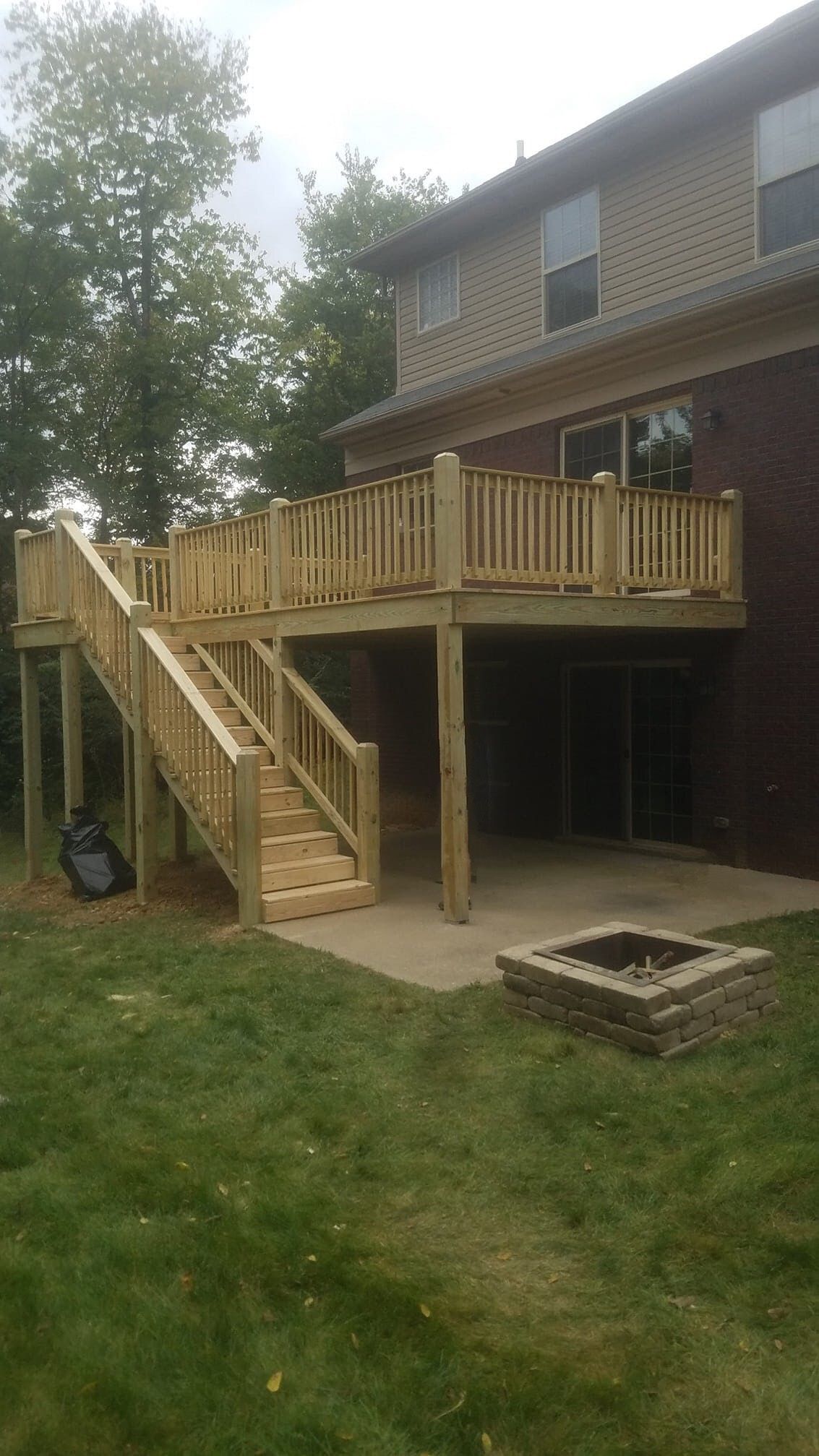 A wooden deck with stairs and a fire pit in the backyard of a house.