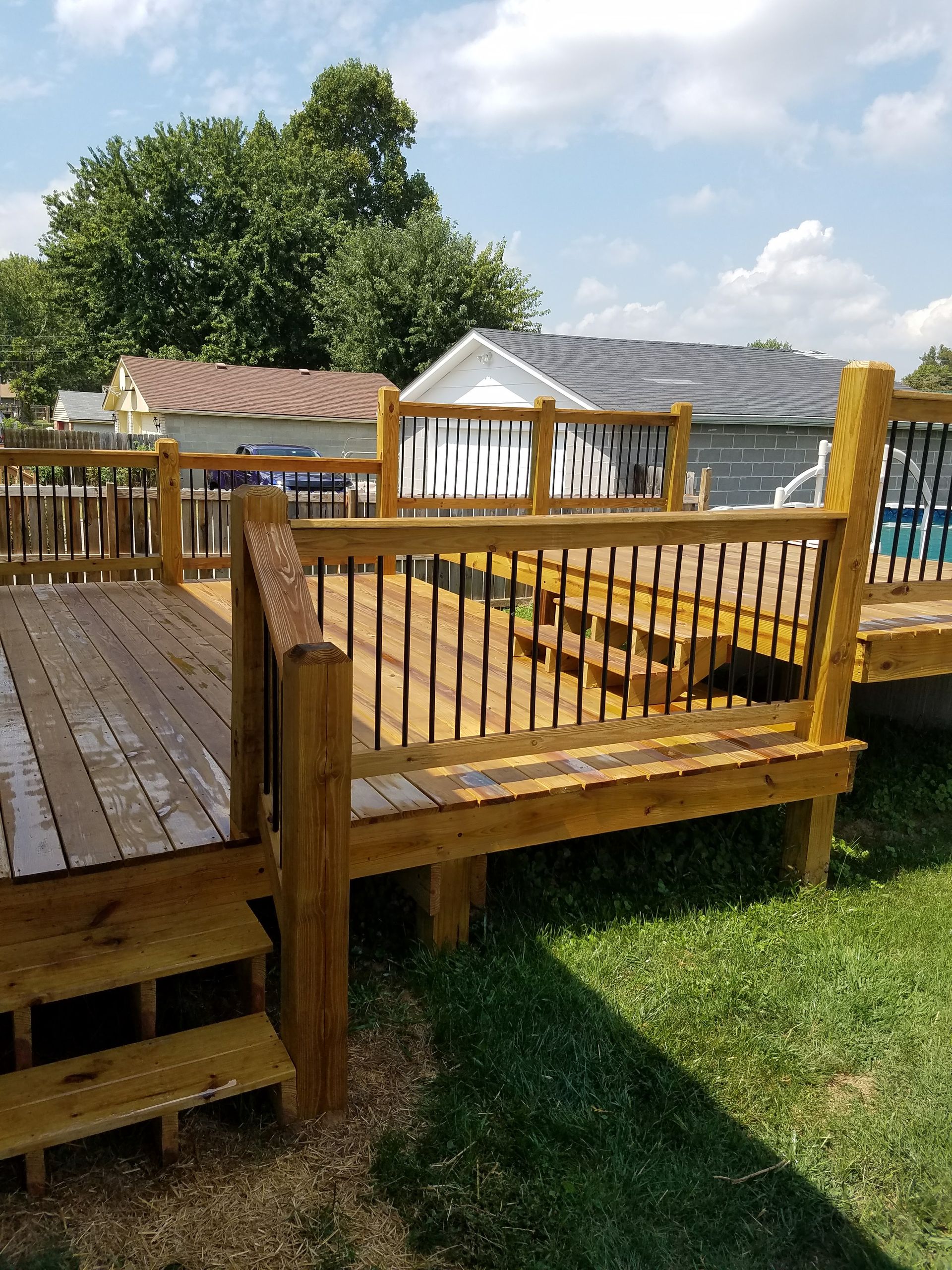 A wooden deck with stairs and a railing in a backyard.