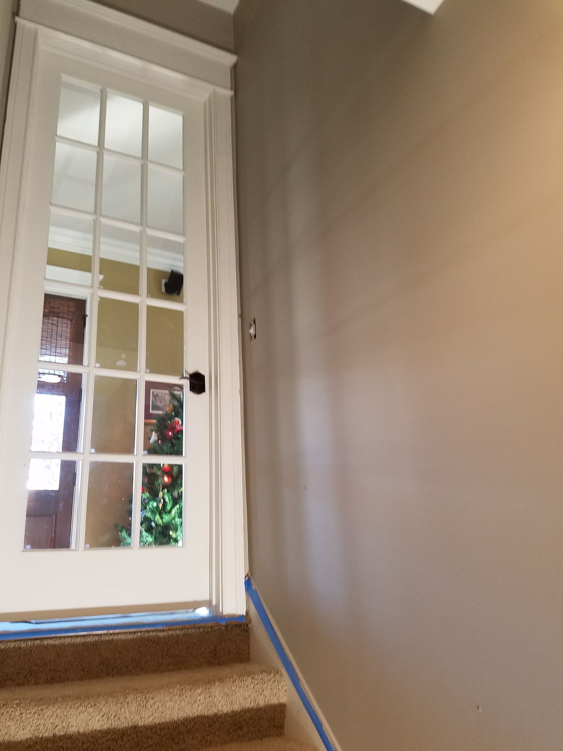 A staircase with a french door and a christmas tree in the background