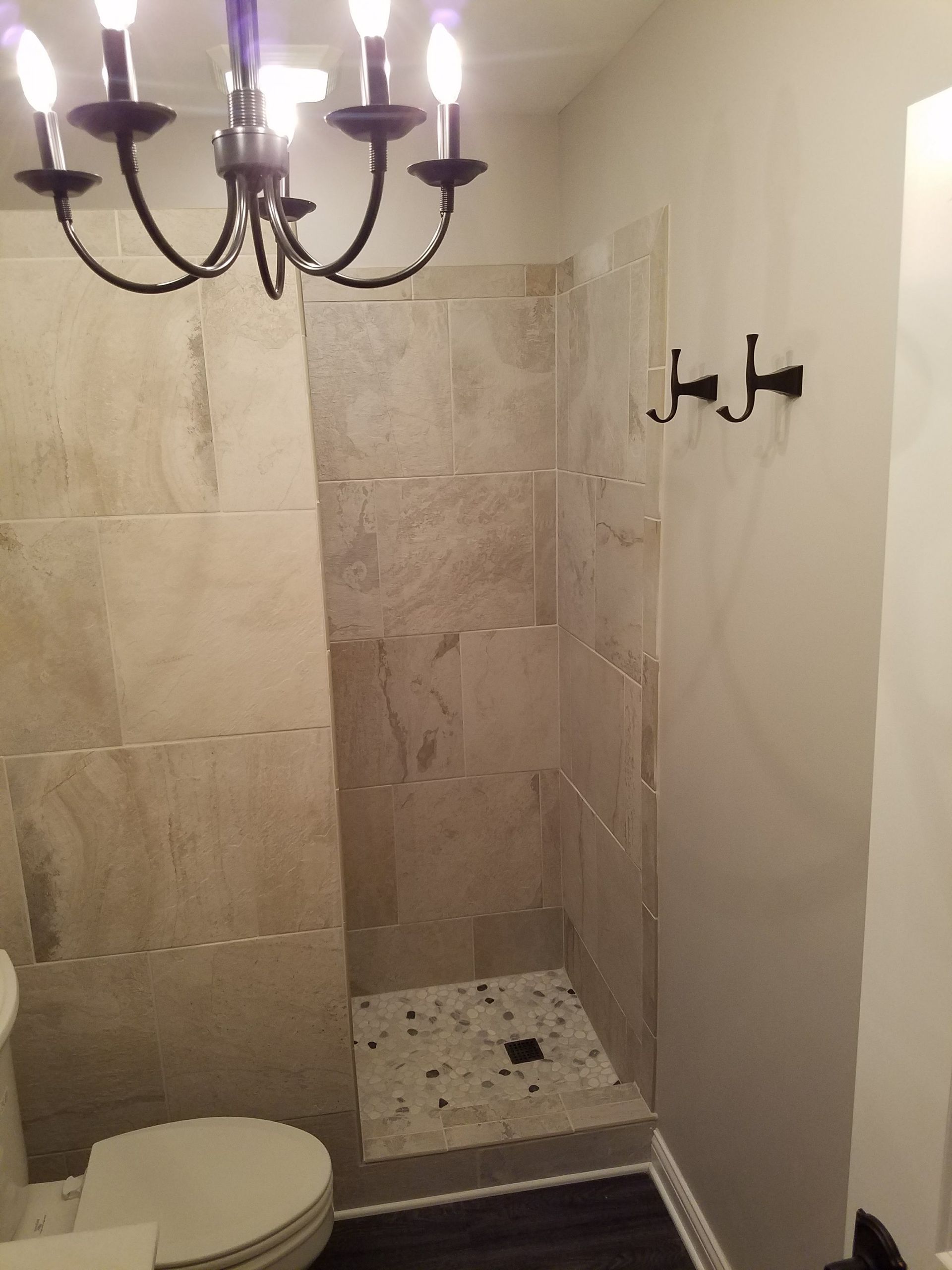A bathroom with a toilet a shower and a chandelier