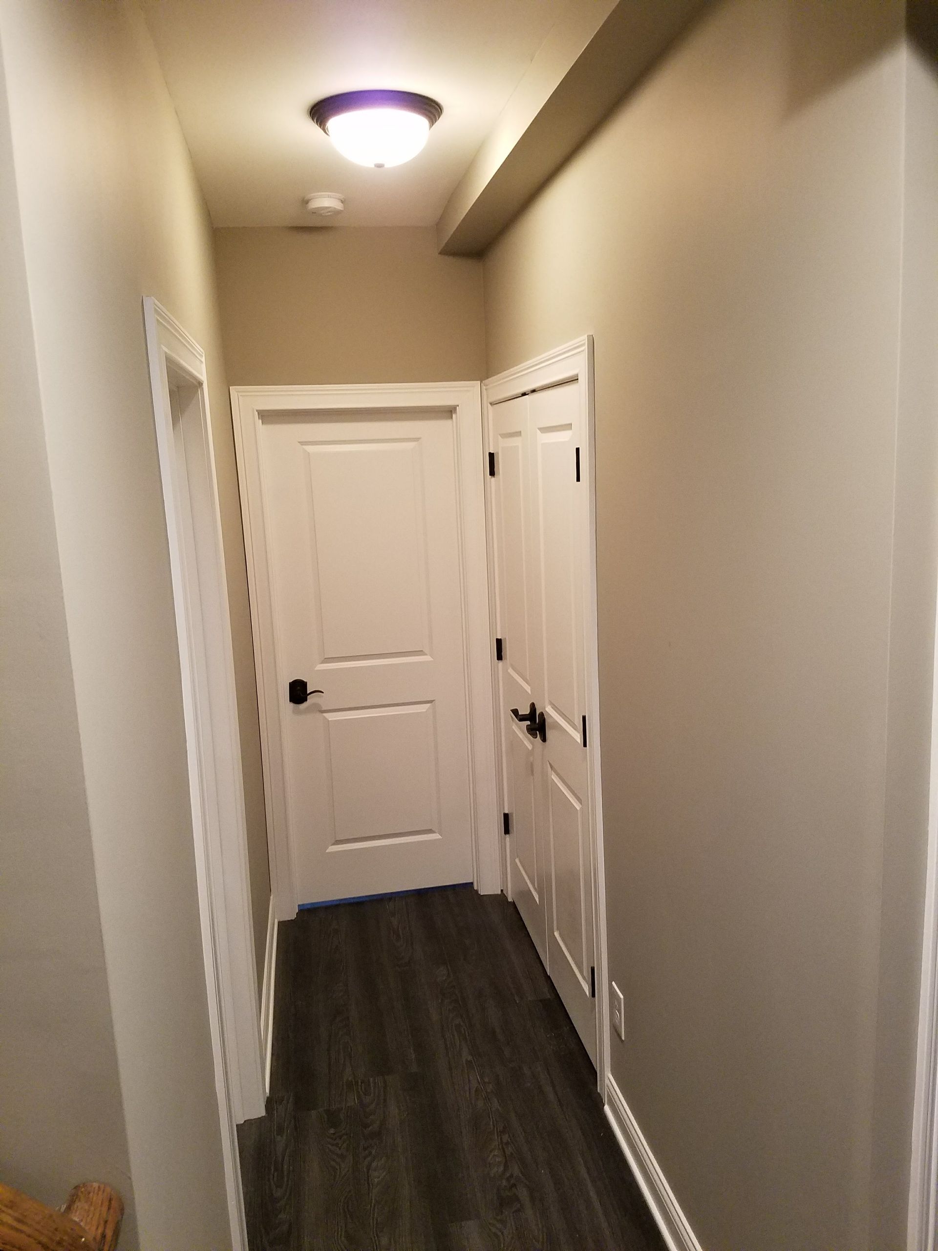 A hallway with white doors and a light on the ceiling.