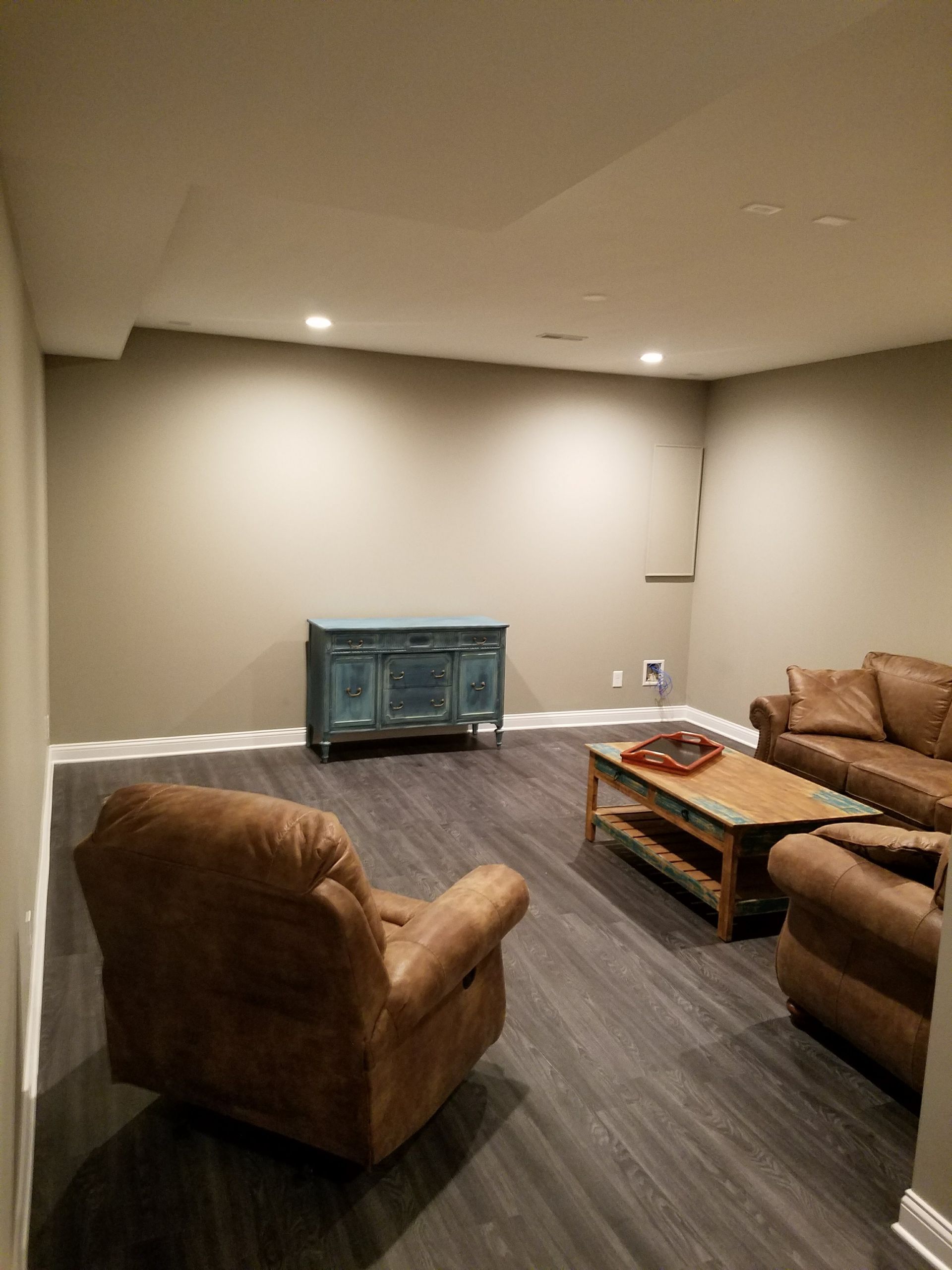 A living room with a couch , chair , coffee table and dresser.