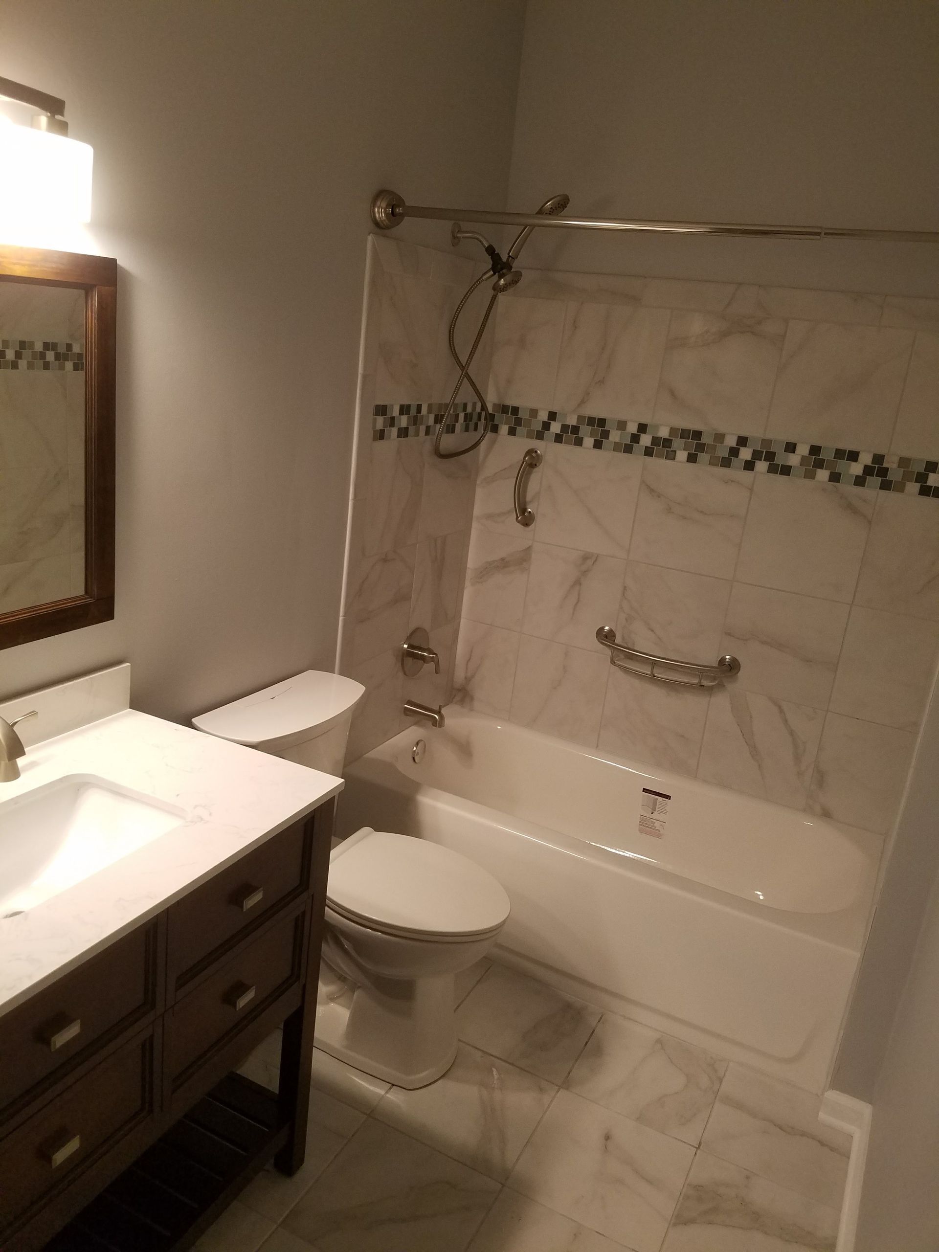 A bathroom with a toilet , sink , bathtub and mirror.