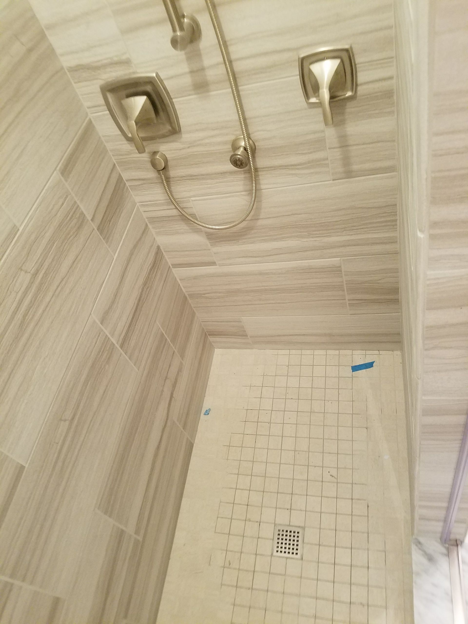 A shower with a tiled floor and a shower head.