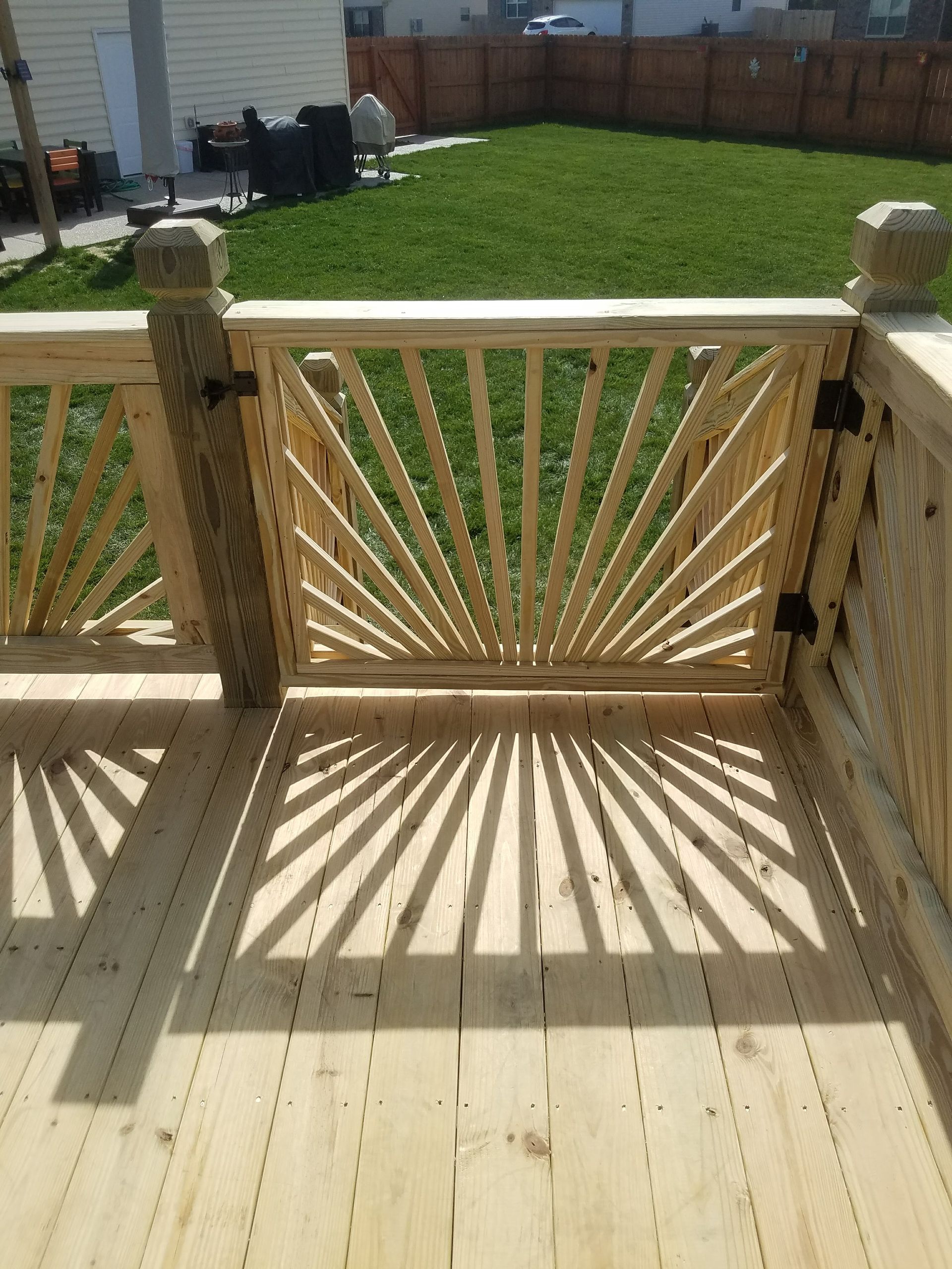 A wooden deck with a wooden gate leading to a grassy yard.