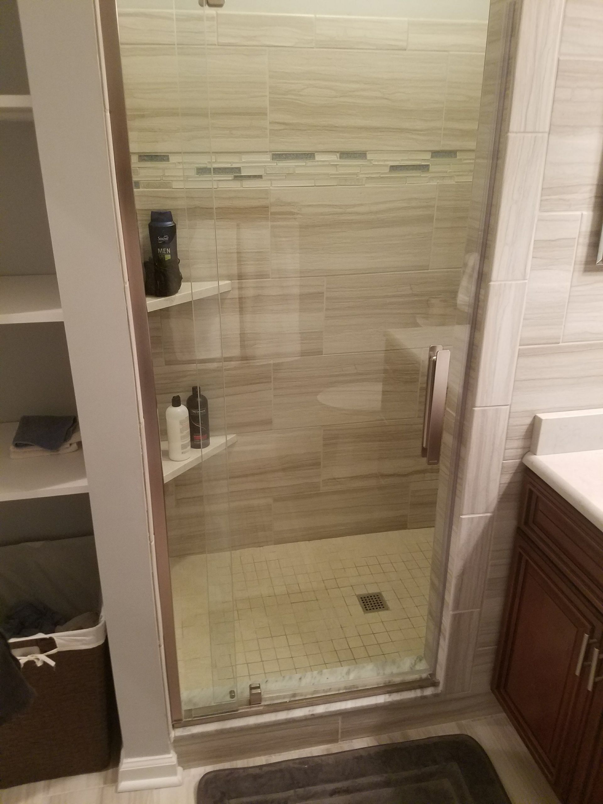 A bathroom with a walk in shower and a sink.