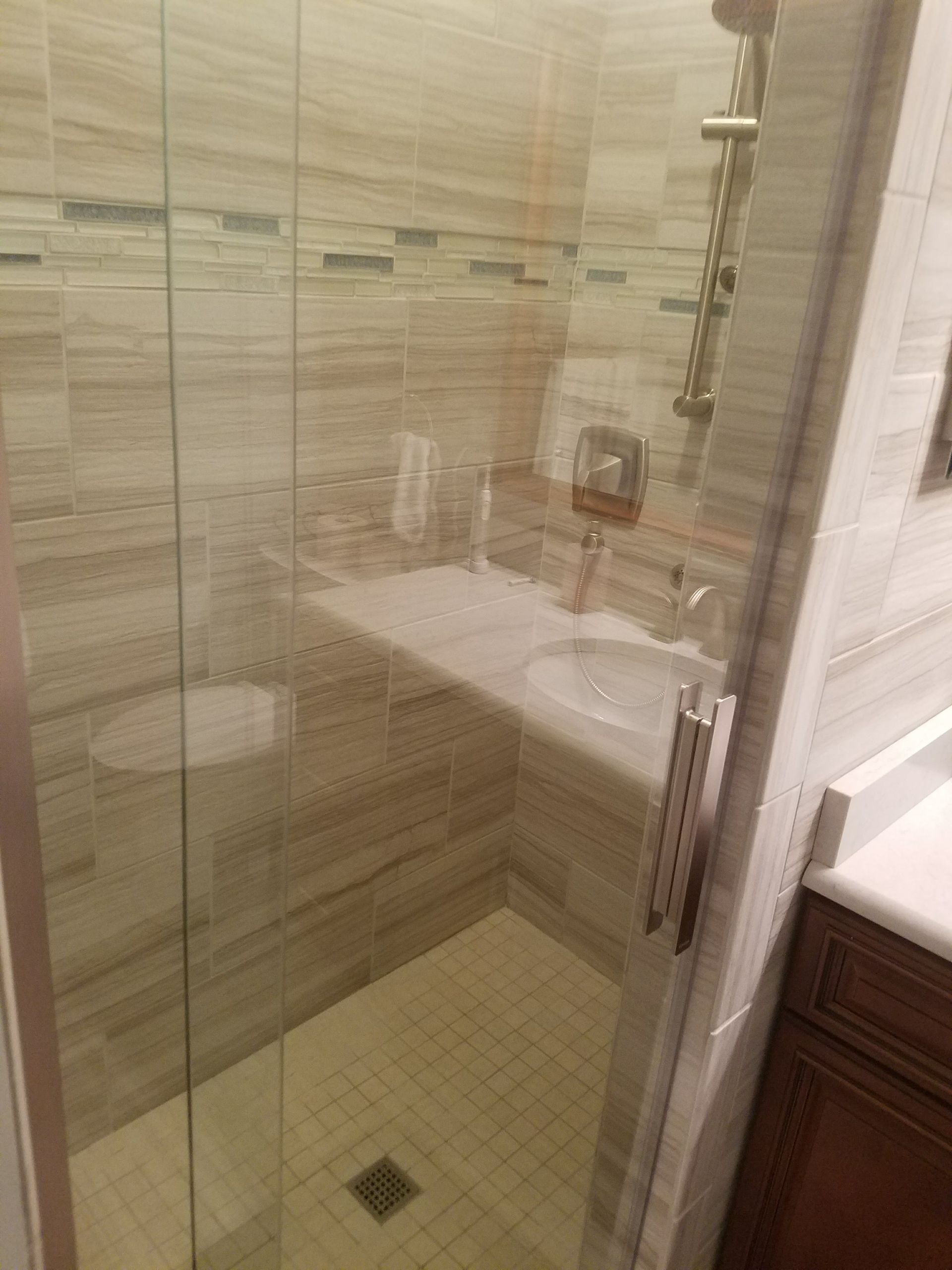 A bathroom with a walk in shower , sink and toilet.