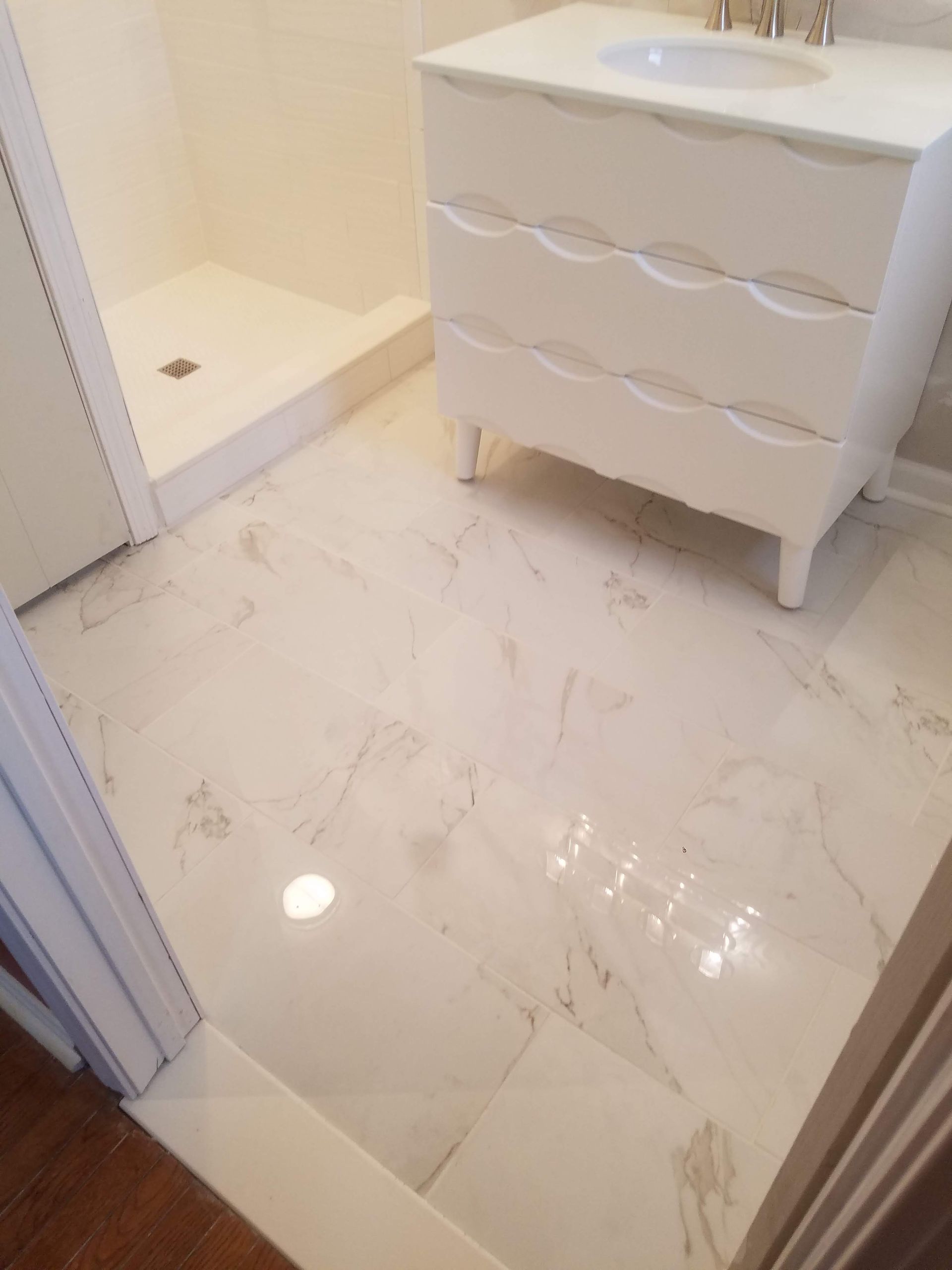 A bathroom with a sink , dresser , and shower.