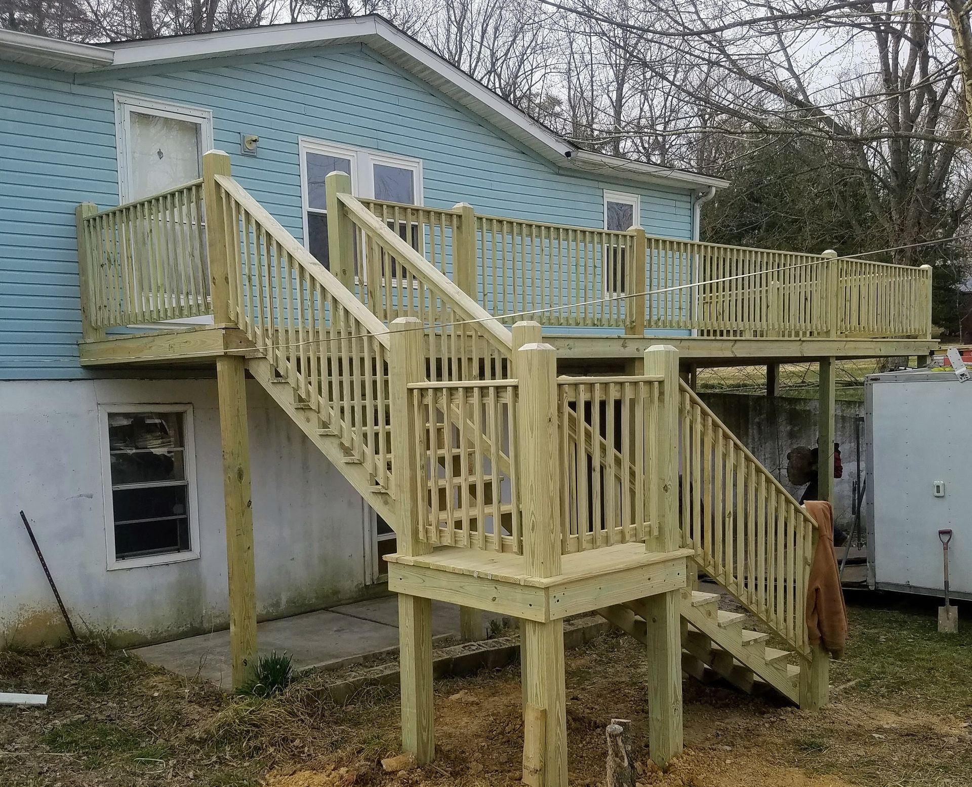 A blue house with a wooden deck and stairs
