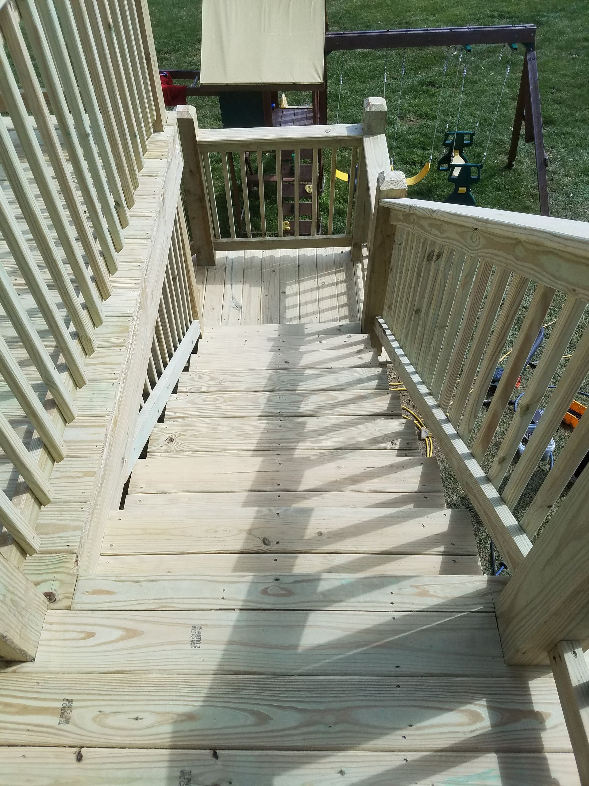 A wooden deck with stairs leading up to a playground