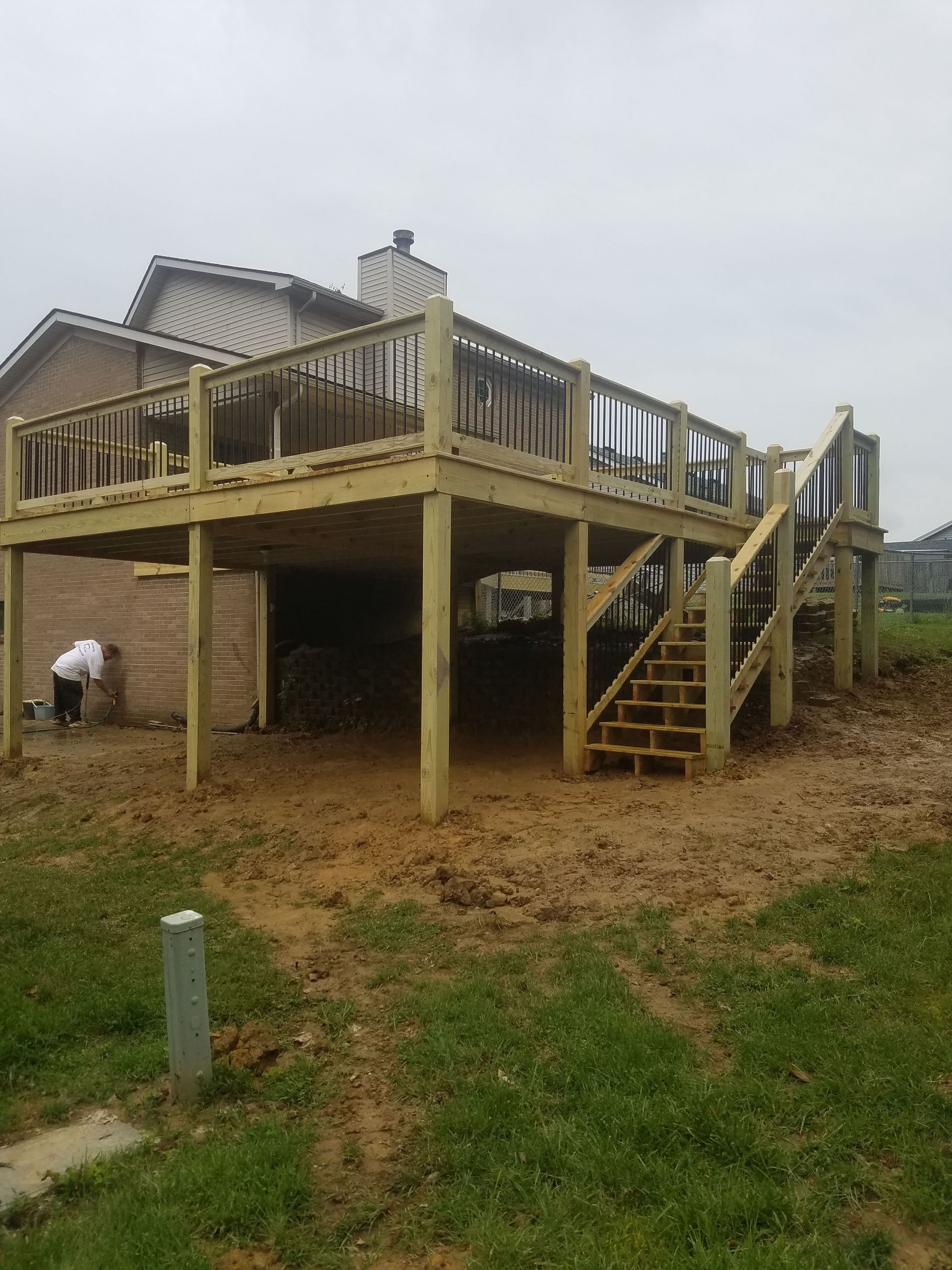 A large wooden deck with stairs is being built in front of a house.