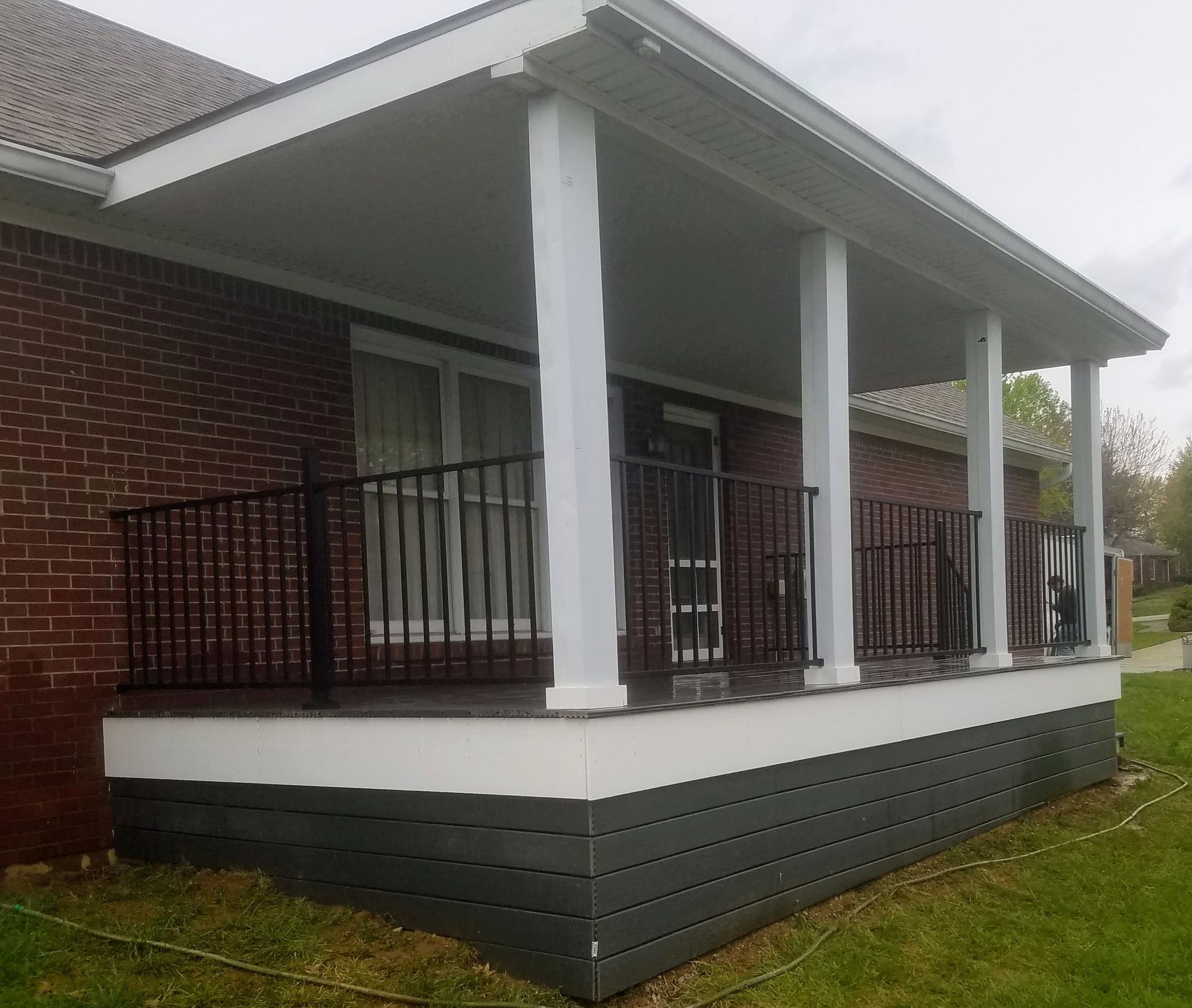 A brick house with a porch and a black railing.