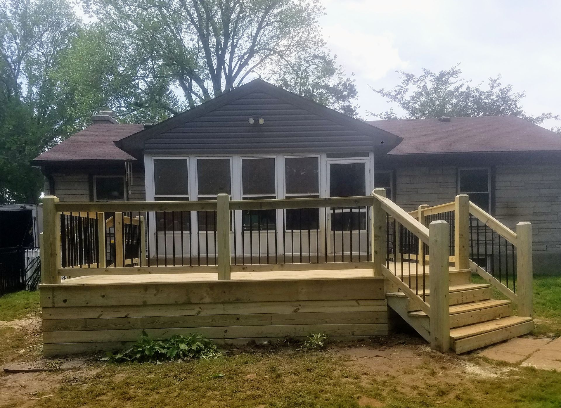 A wooden deck with stairs is in front of a house.