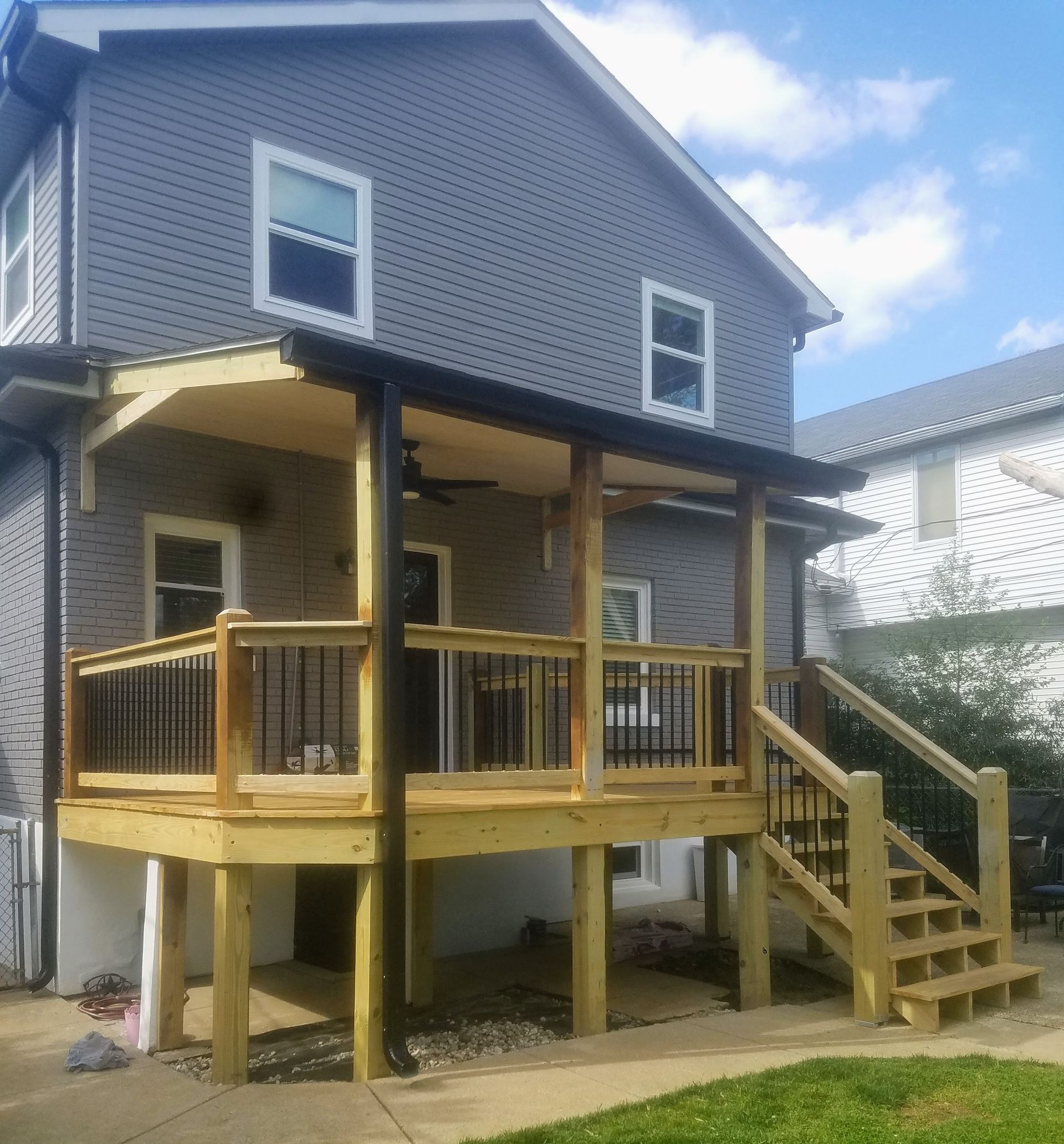 A gray house with a wooden deck and stairs