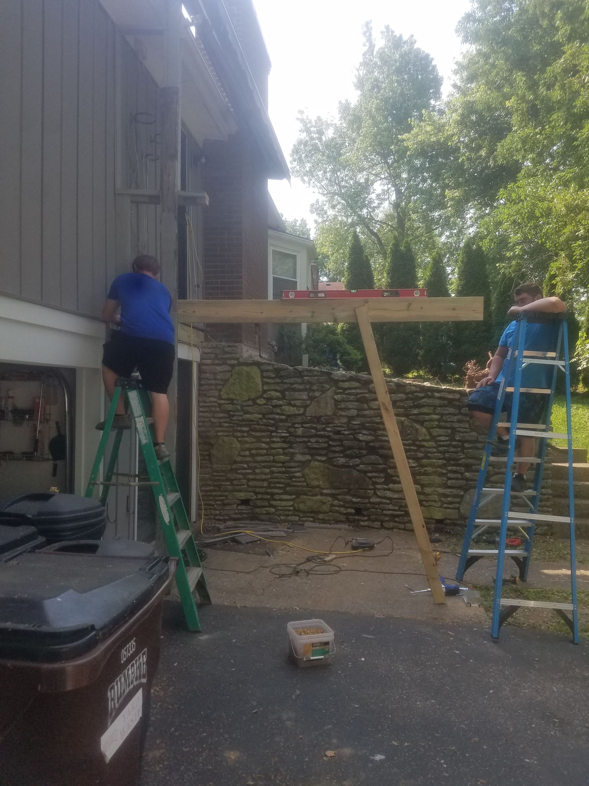 A man is sitting on a ladder in front of a house.