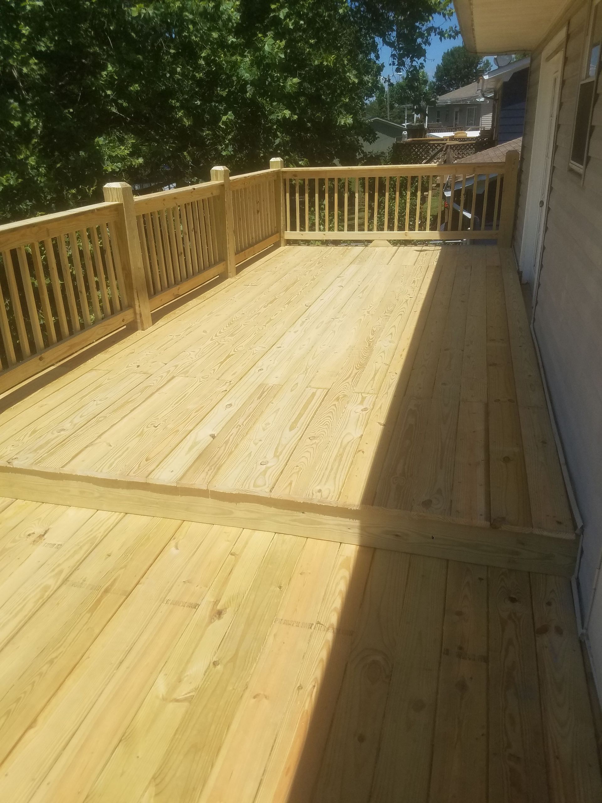 A large wooden deck with a wooden railing and fence.