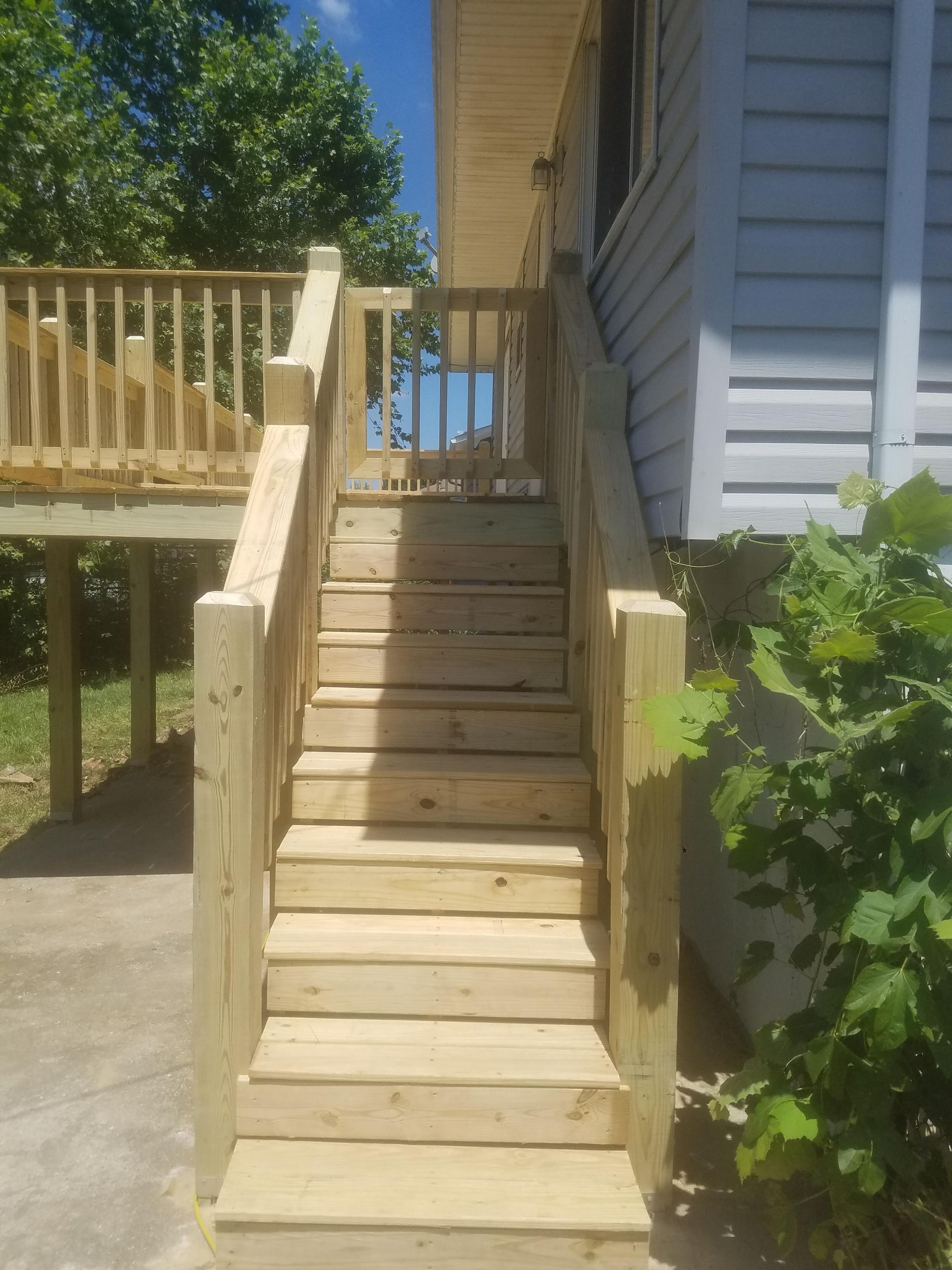 A wooden deck with stairs leading up to it next to a house.