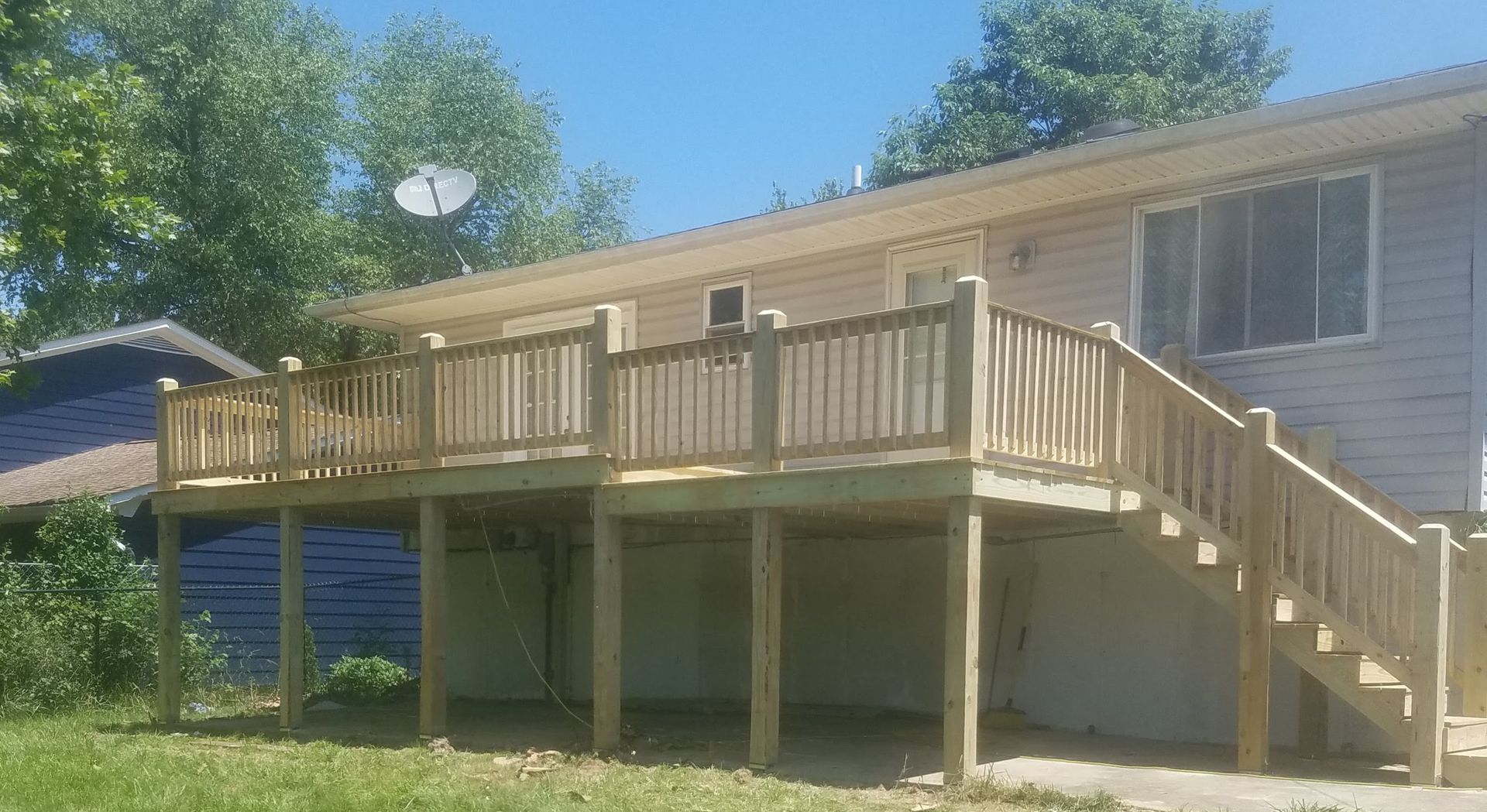 A house with a large wooden deck and stairs in front of it.