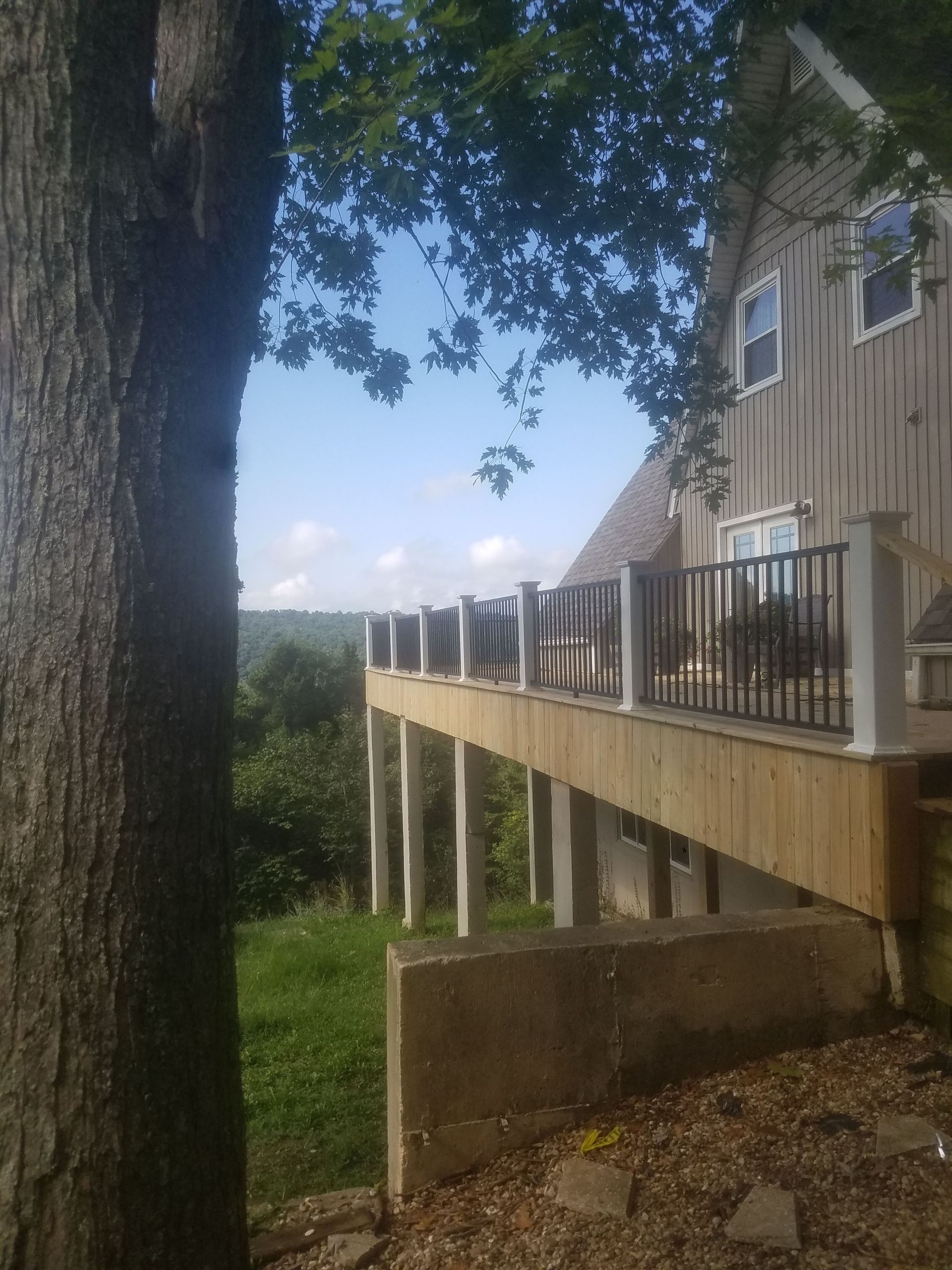 A house with a wooden deck and a tree in front of it