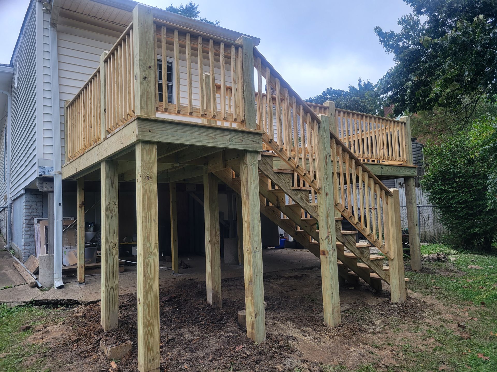 A wooden deck with stairs is being built in the backyard of a house.