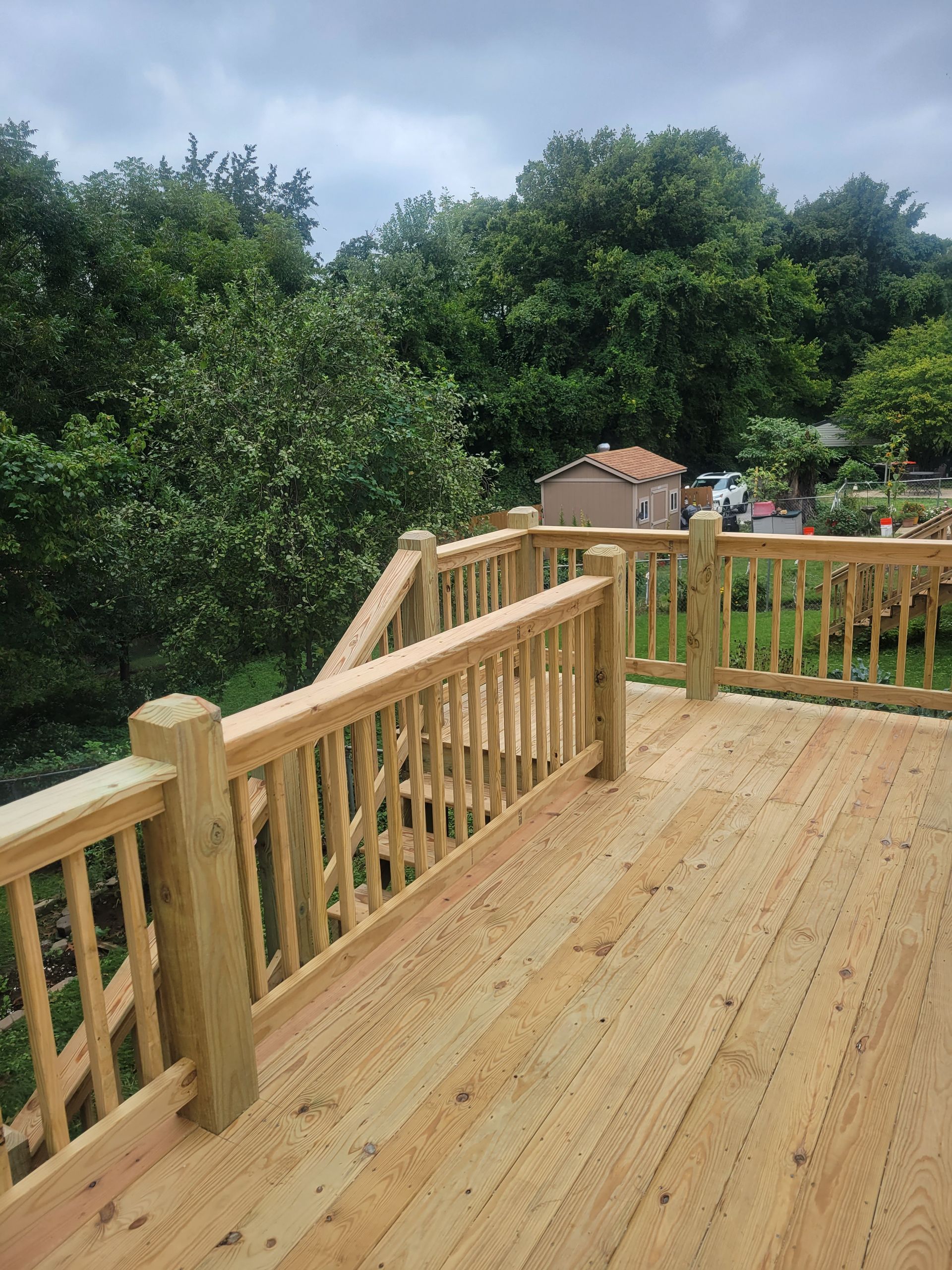 A wooden deck with a wooden railing and stairs leading up to it.