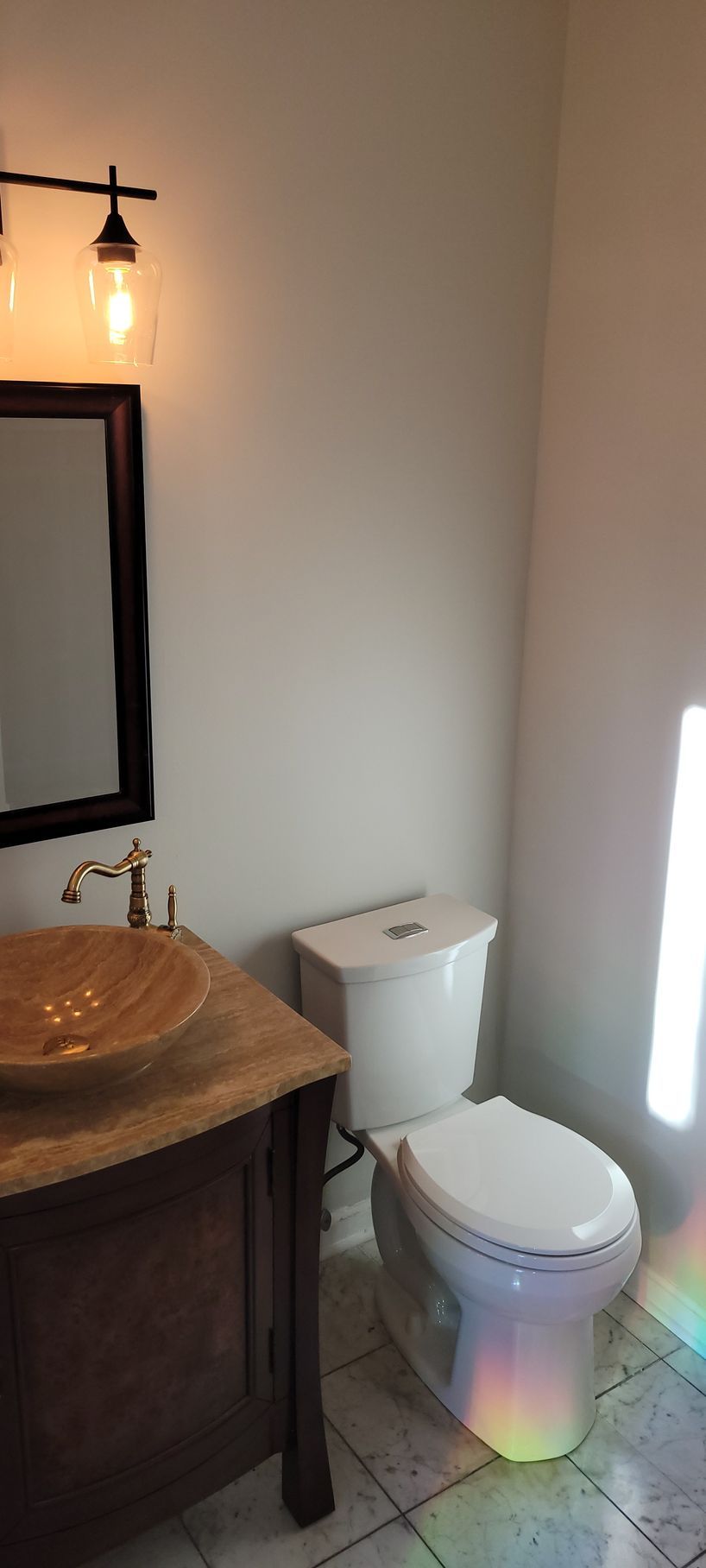 A bathroom with a toilet , sink and mirror.