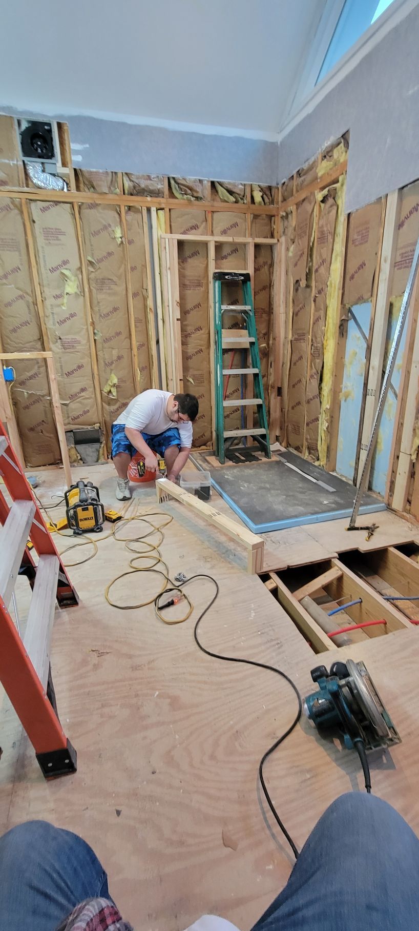A man is working on a wooden floor in a room under construction.