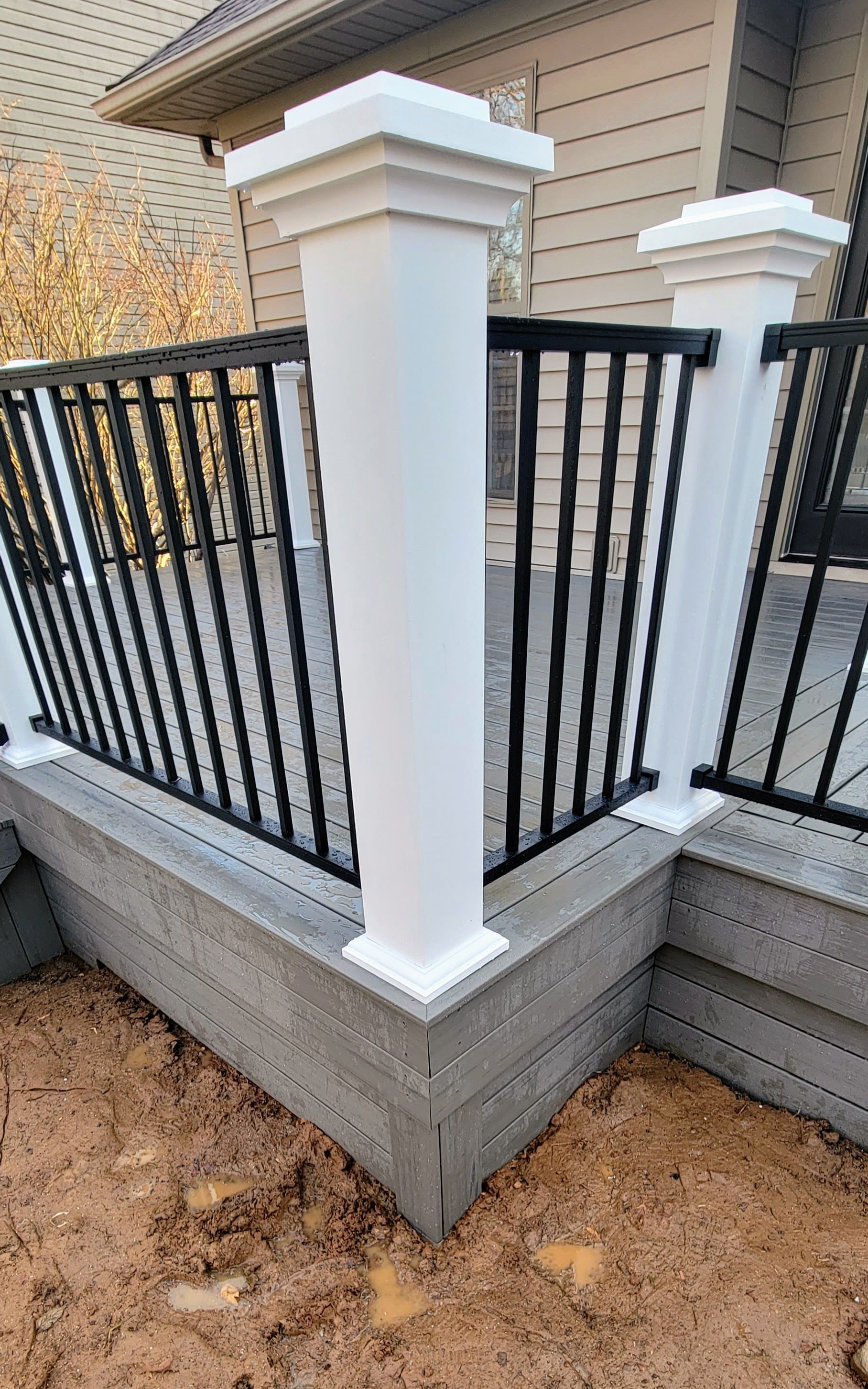A deck with a black railing and white posts.