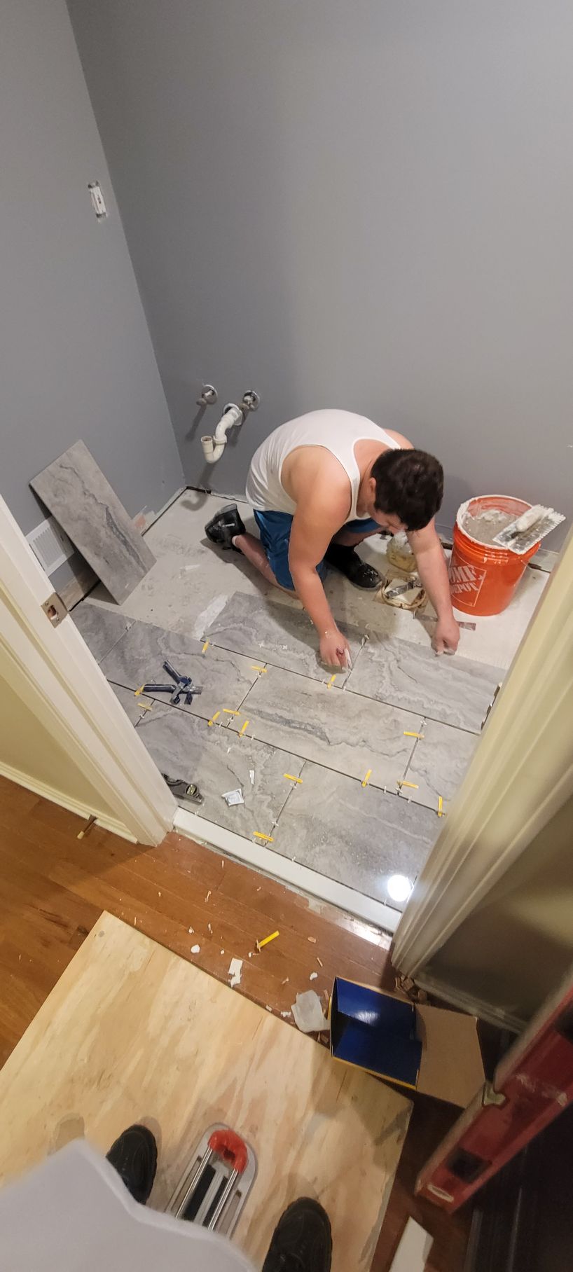 A man is kneeling on the floor in a bathroom.