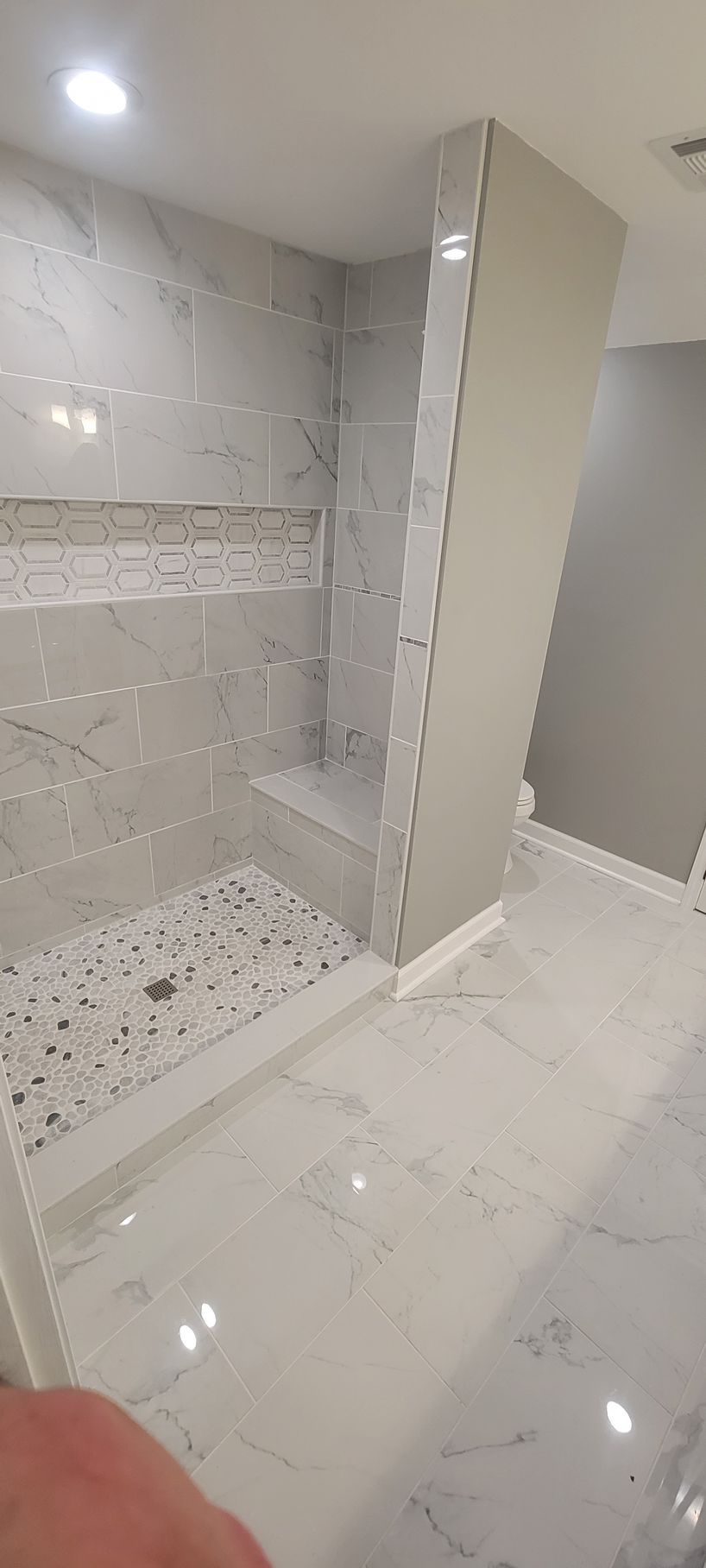 A bathroom with a walk in shower and a marble floor.