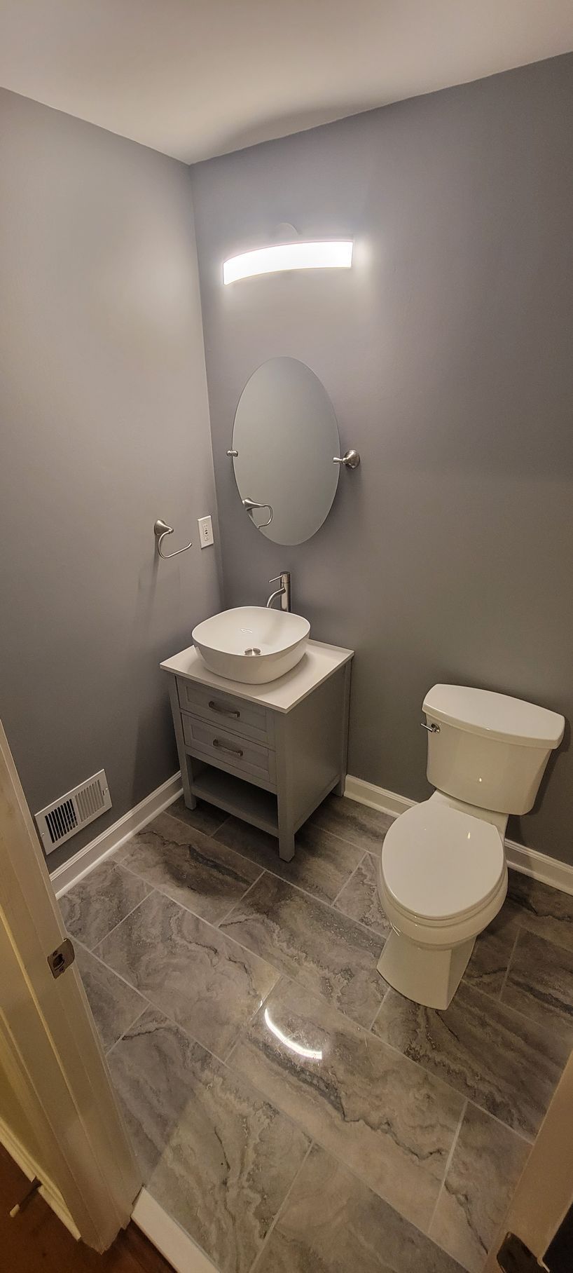 A bathroom with a toilet , sink and mirror.