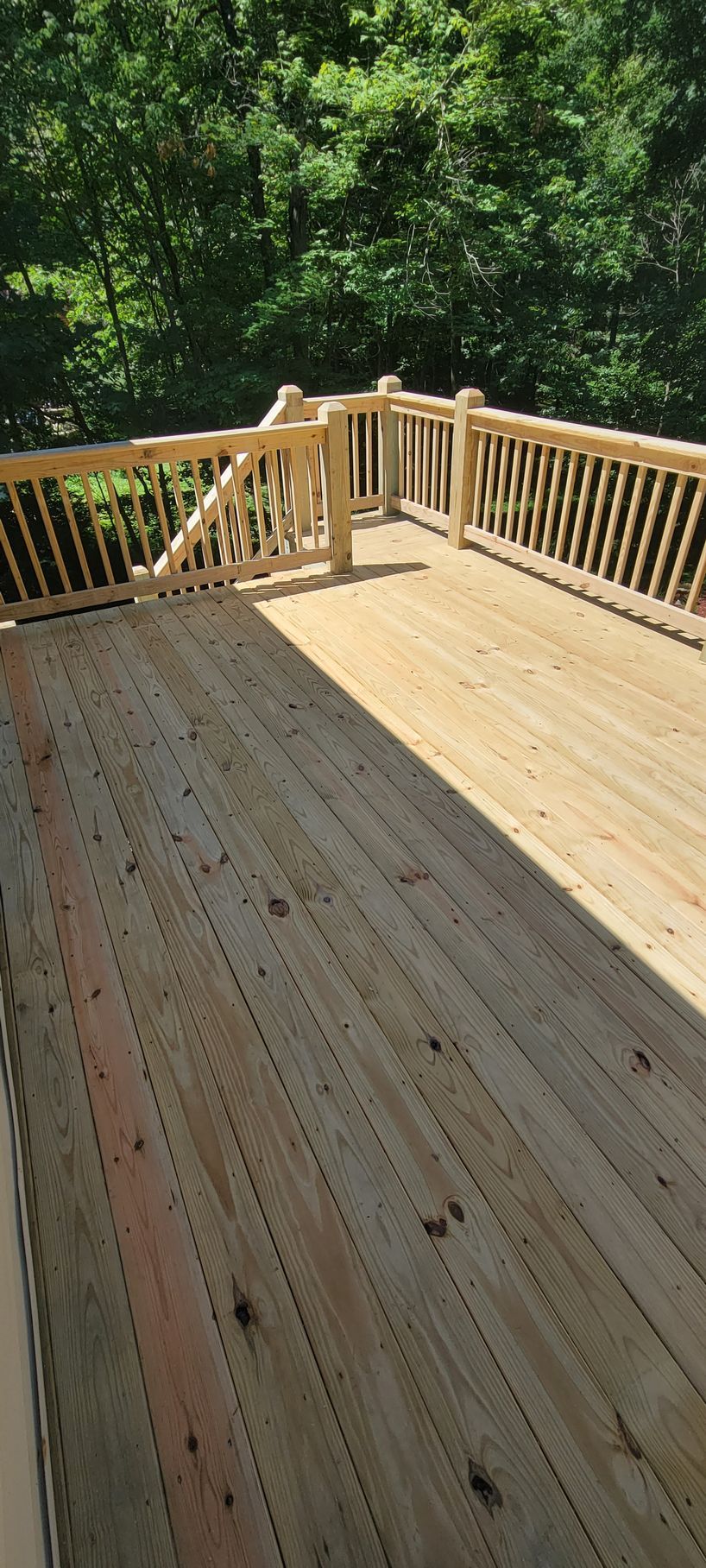 A wooden deck with a wooden railing and trees in the background.