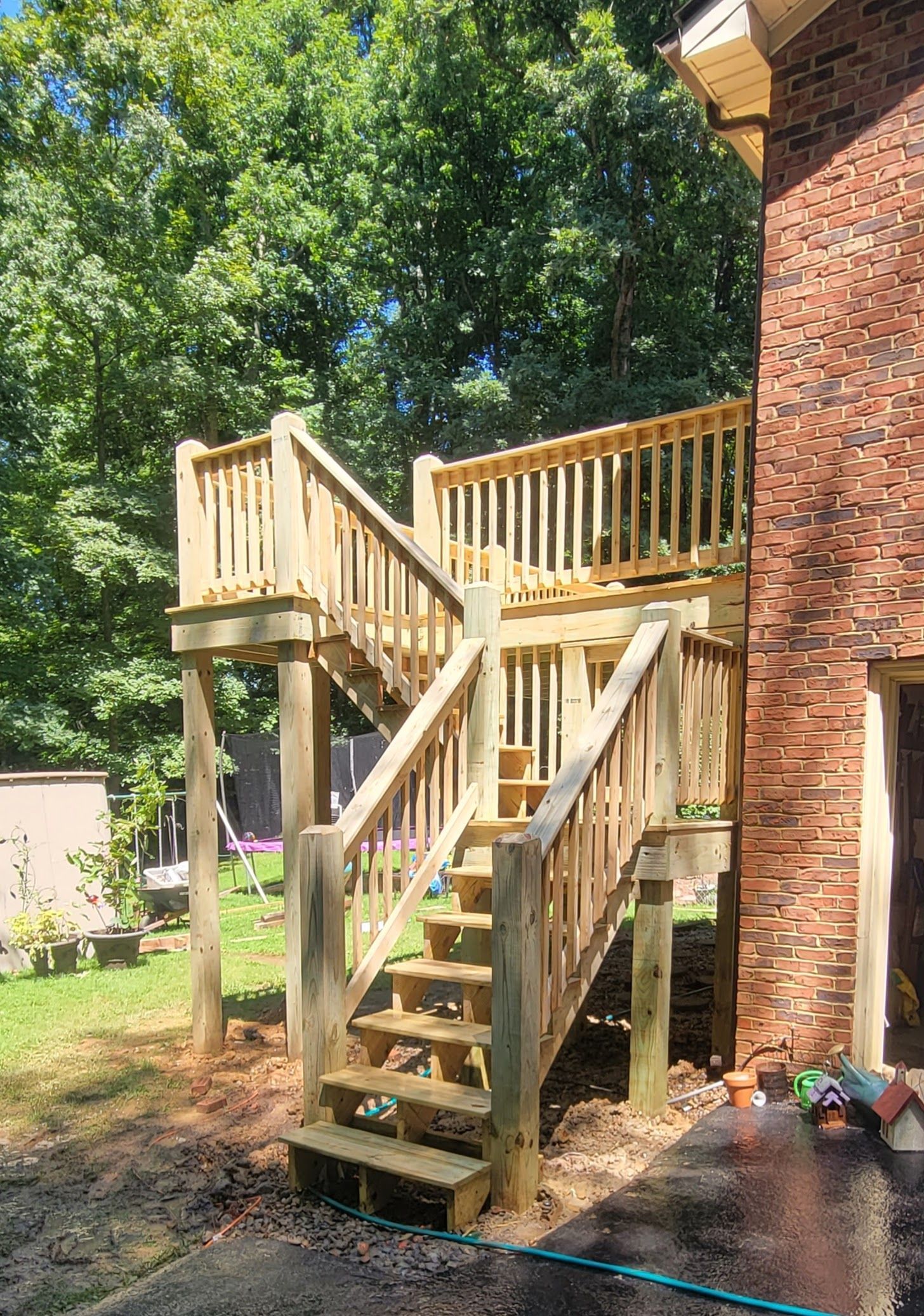 A wooden deck with stairs leading up to it next to a brick building.