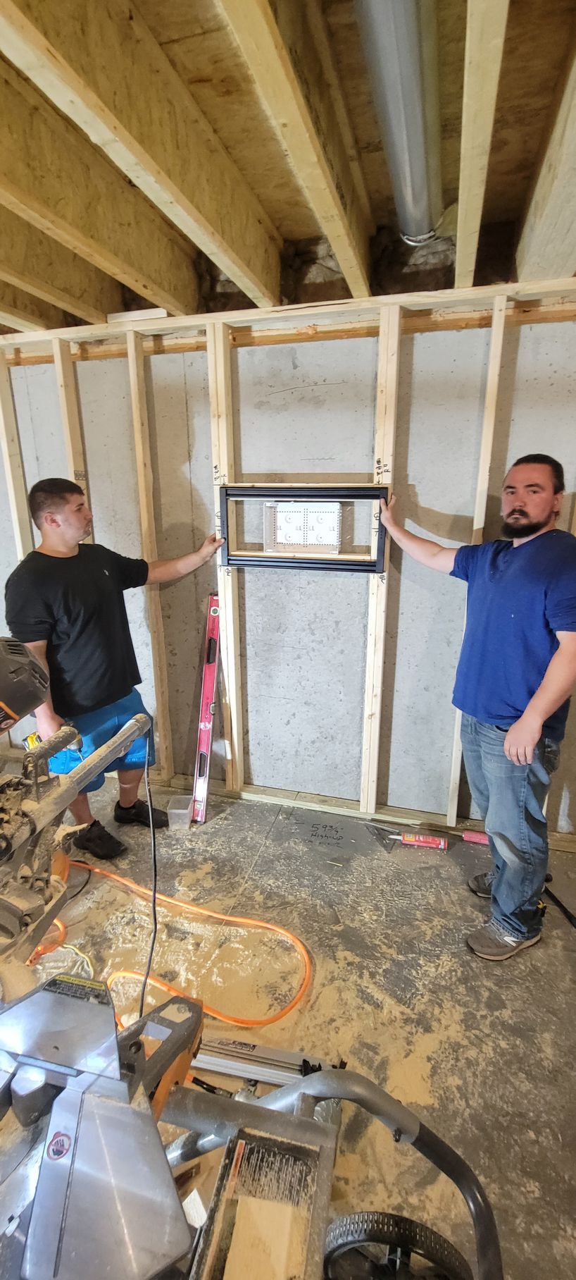 Two men are standing next to each other in a room under construction.