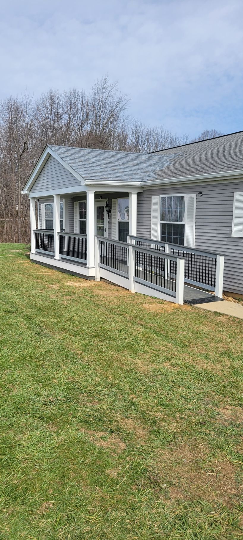 A mobile home with a large porch and a ramp.