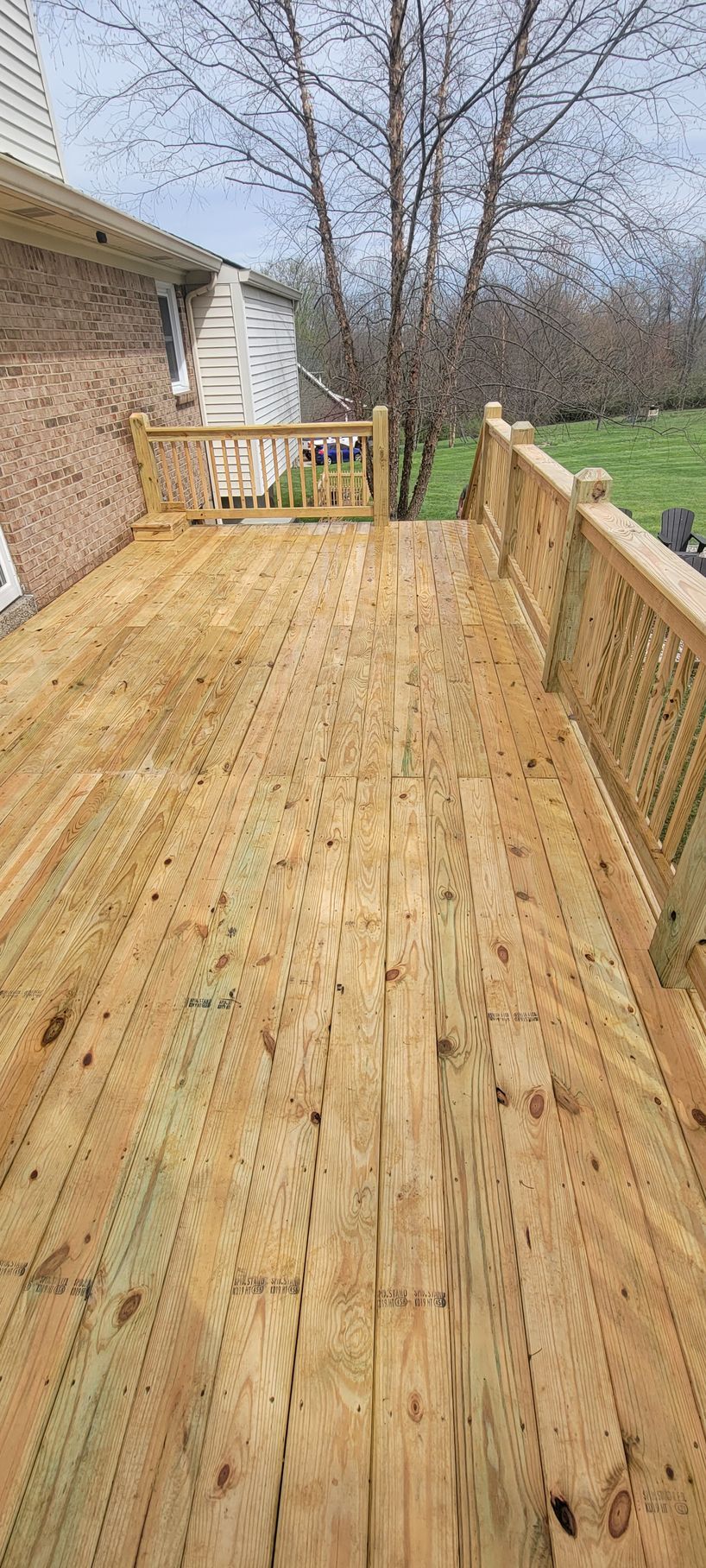 A wooden deck with a railing and stairs leading to a house.
