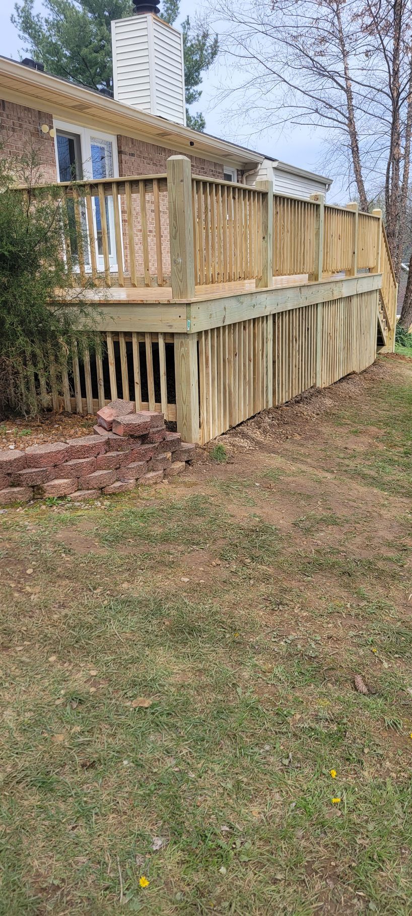 A wooden deck is sitting in the backyard of a house.