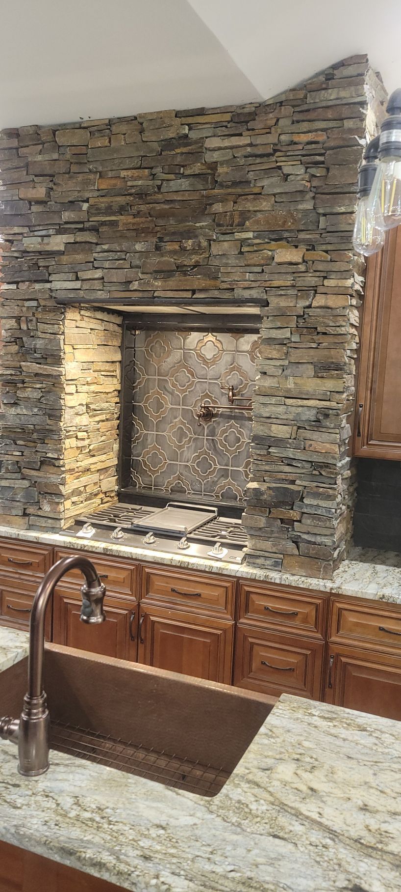 A kitchen with a stone fireplace and a sink.