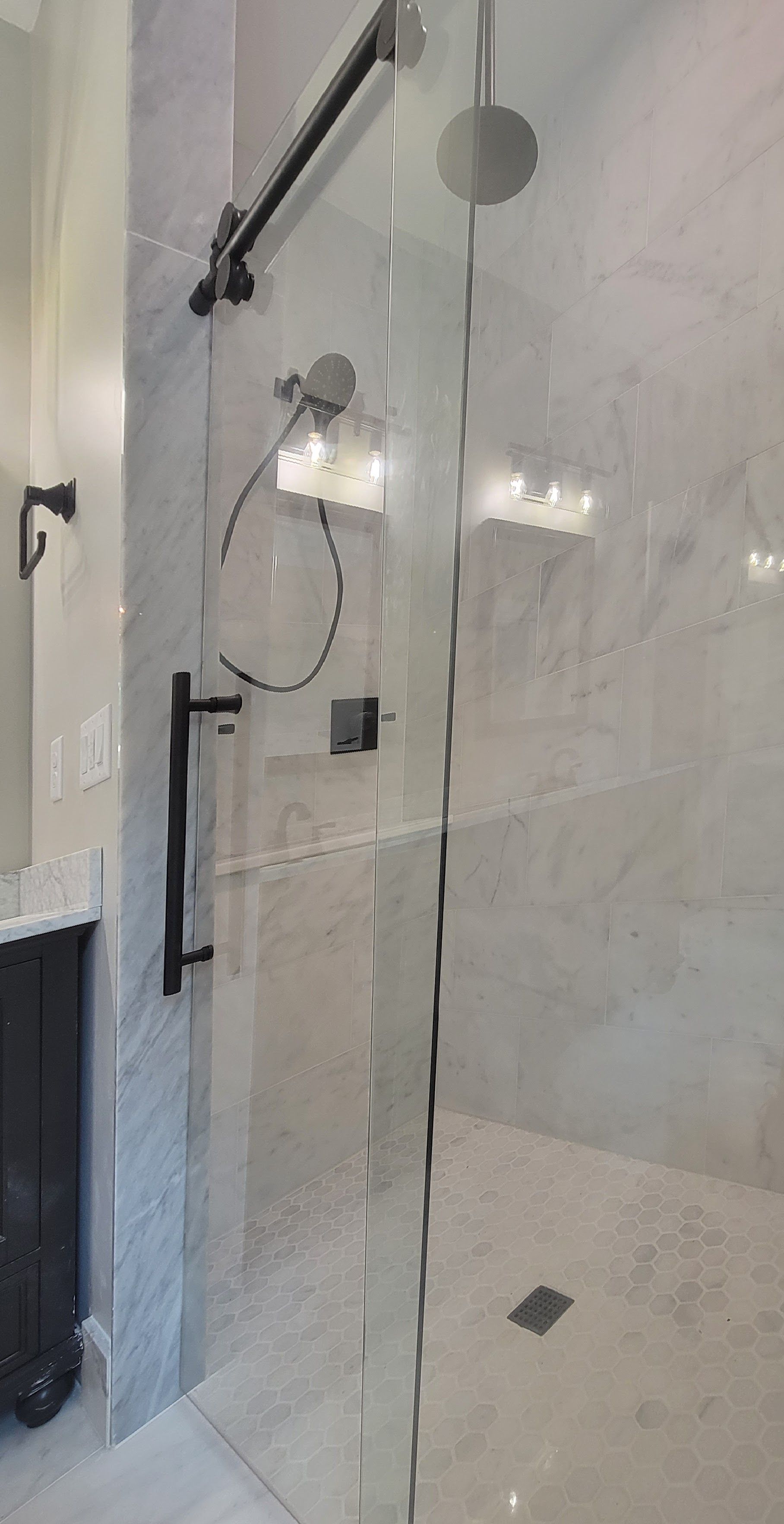 A bathroom with a walk in shower with a glass door.