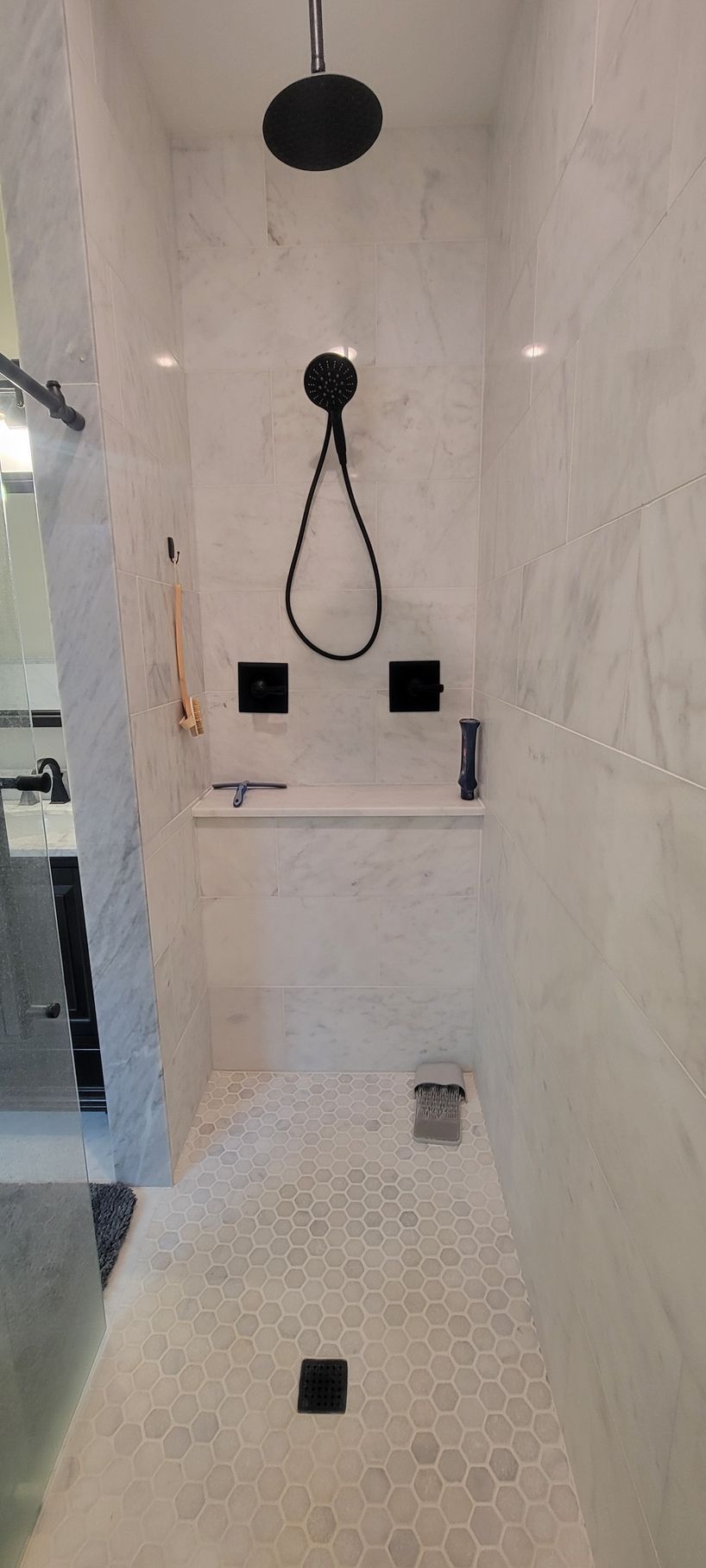 A bathroom with a walk in shower and a black shower head.