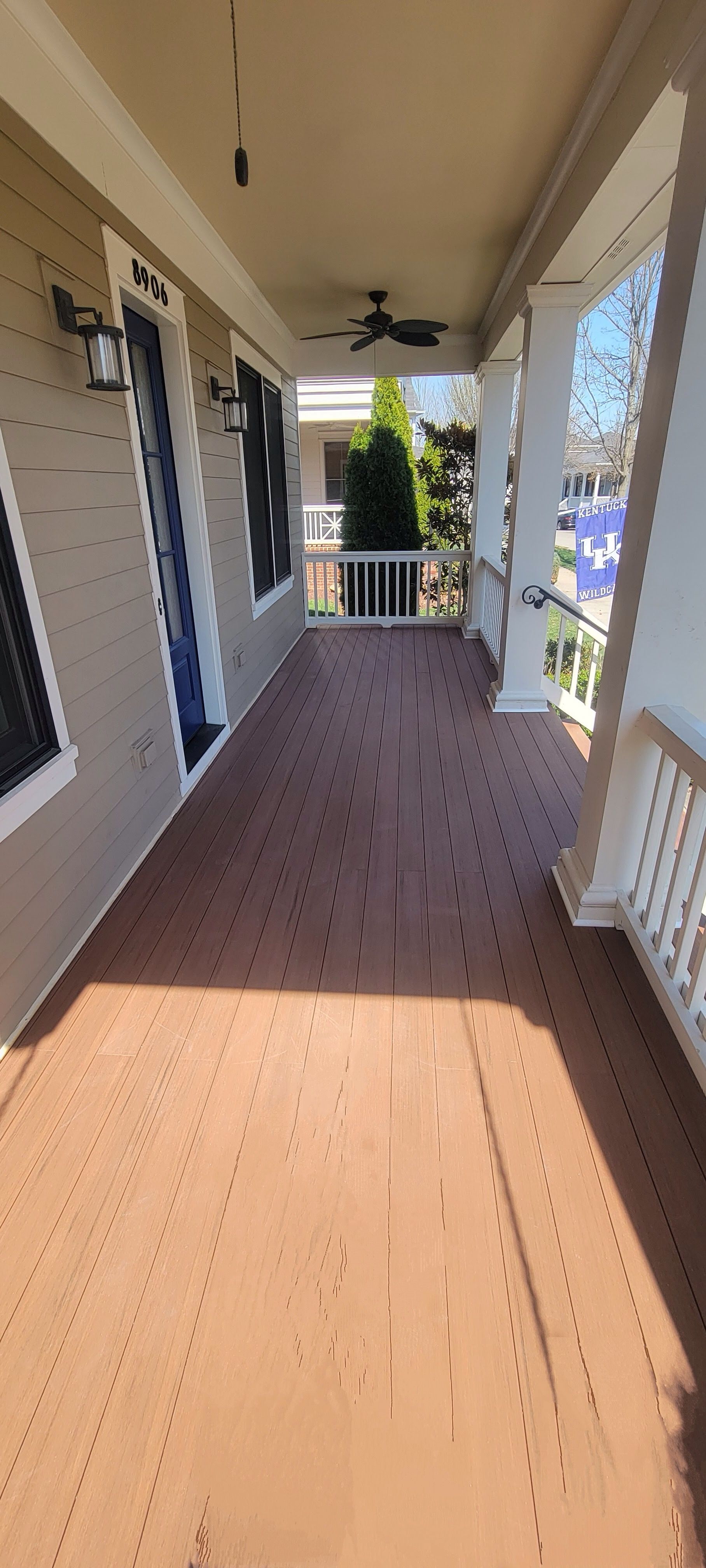 A large porch with a wooden floor and a ceiling fan.