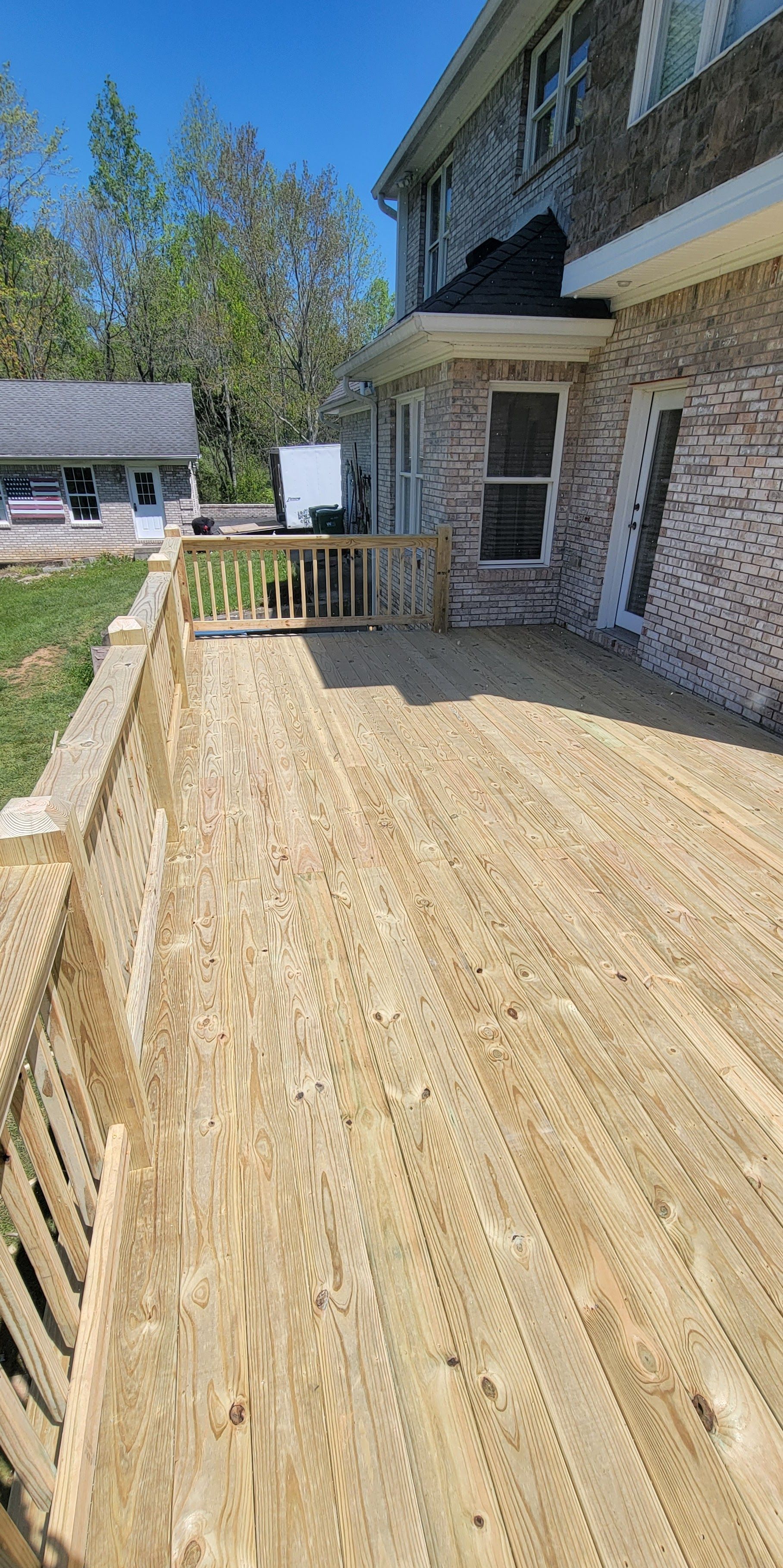 A wooden deck is being built in front of a brick house.