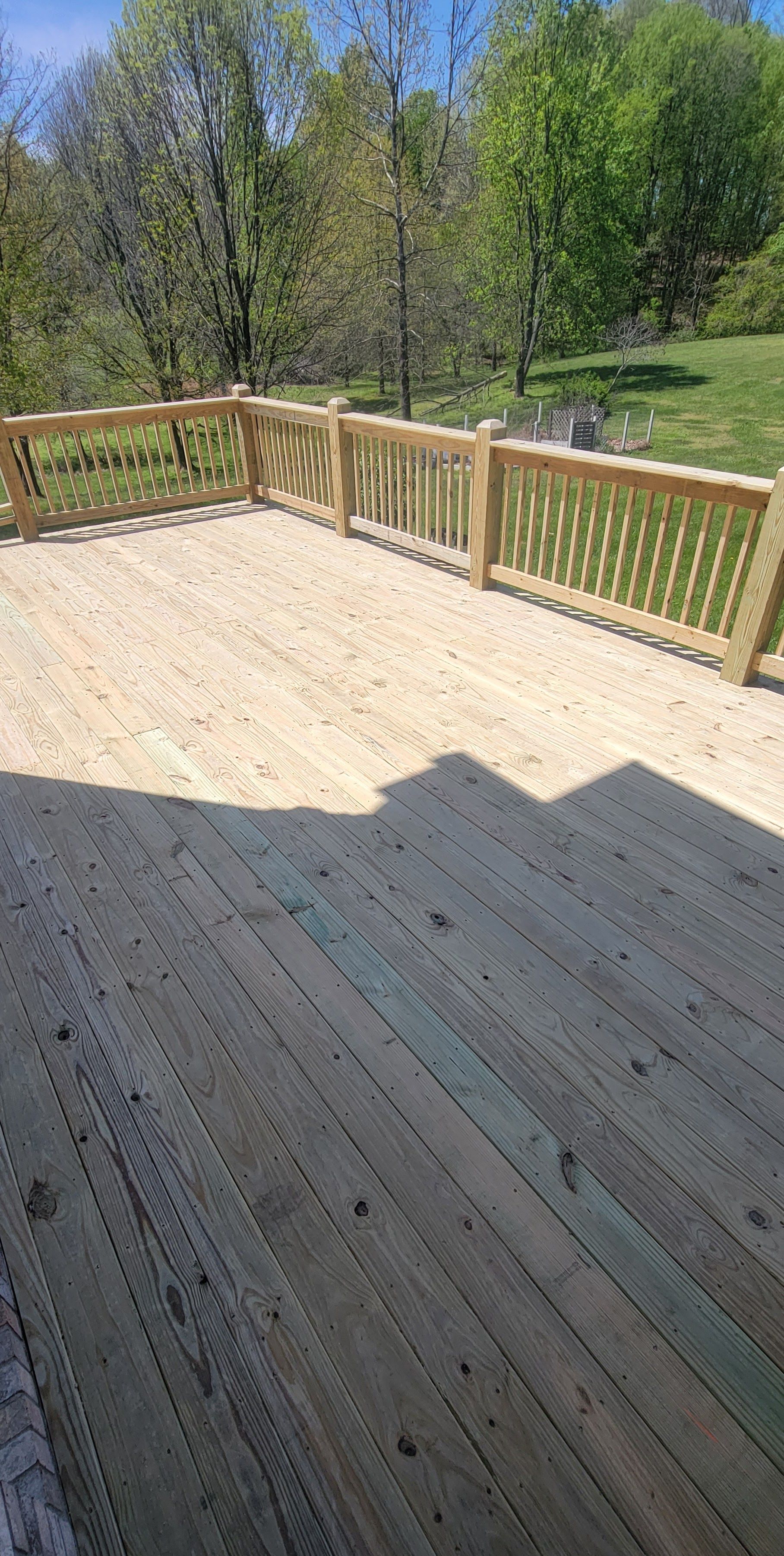 A wooden deck with a wooden fence and trees in the background.